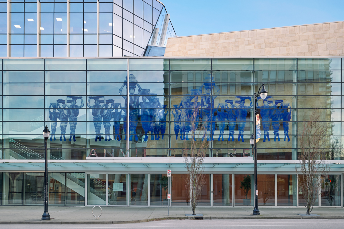 A photograph of many people in blue across a glass building