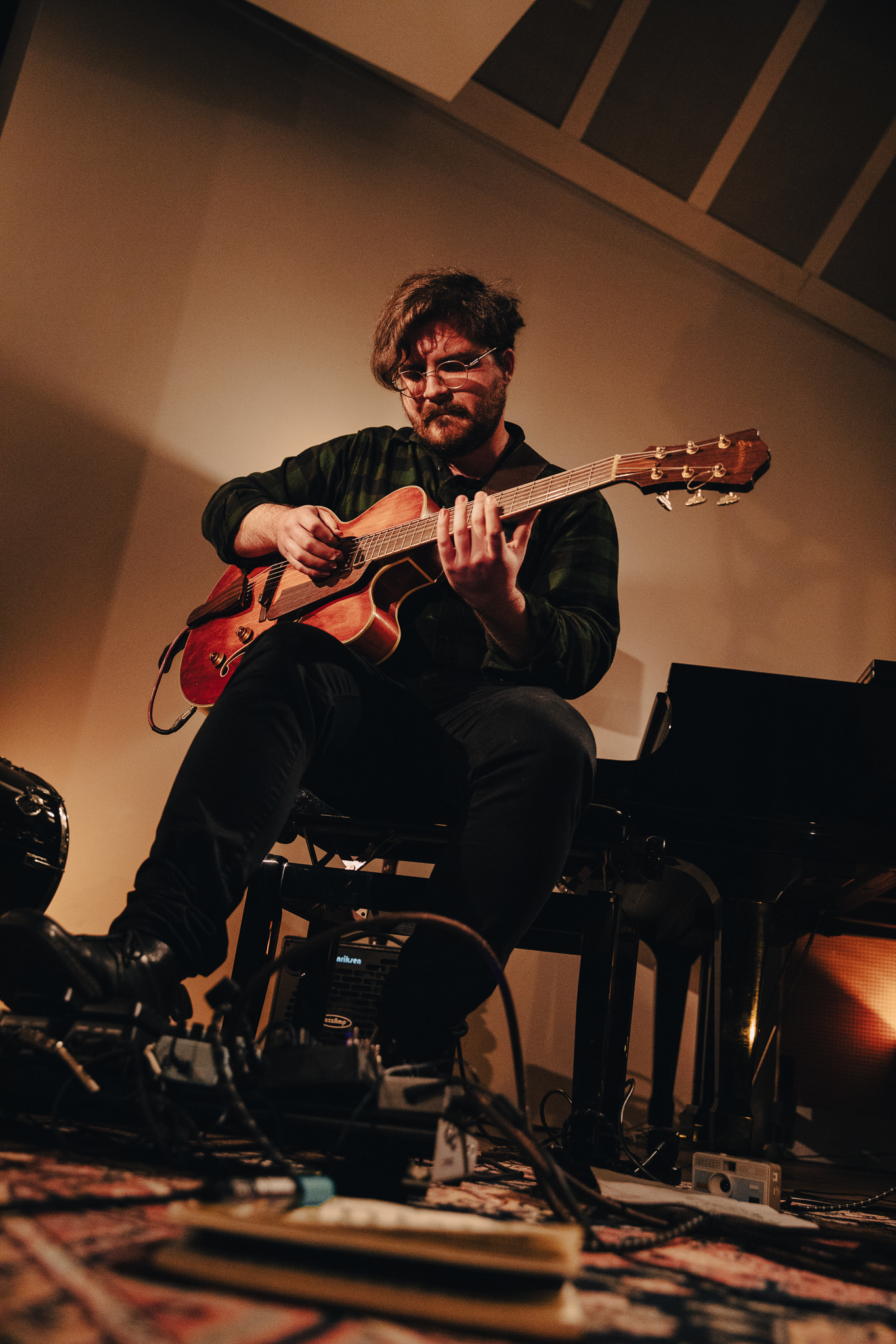 Upward shot of a man playing guitar sitting on a piano bench 