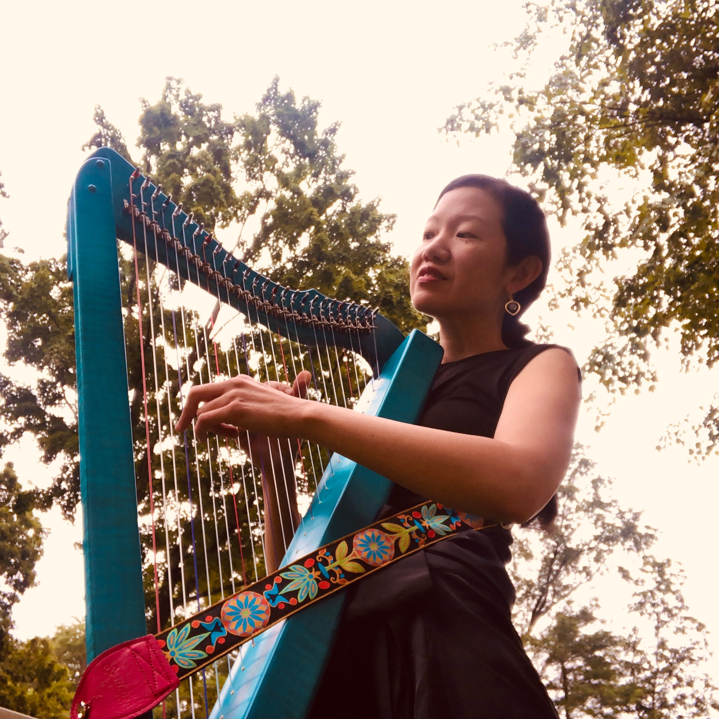 Woman standing outside playing a blue harp