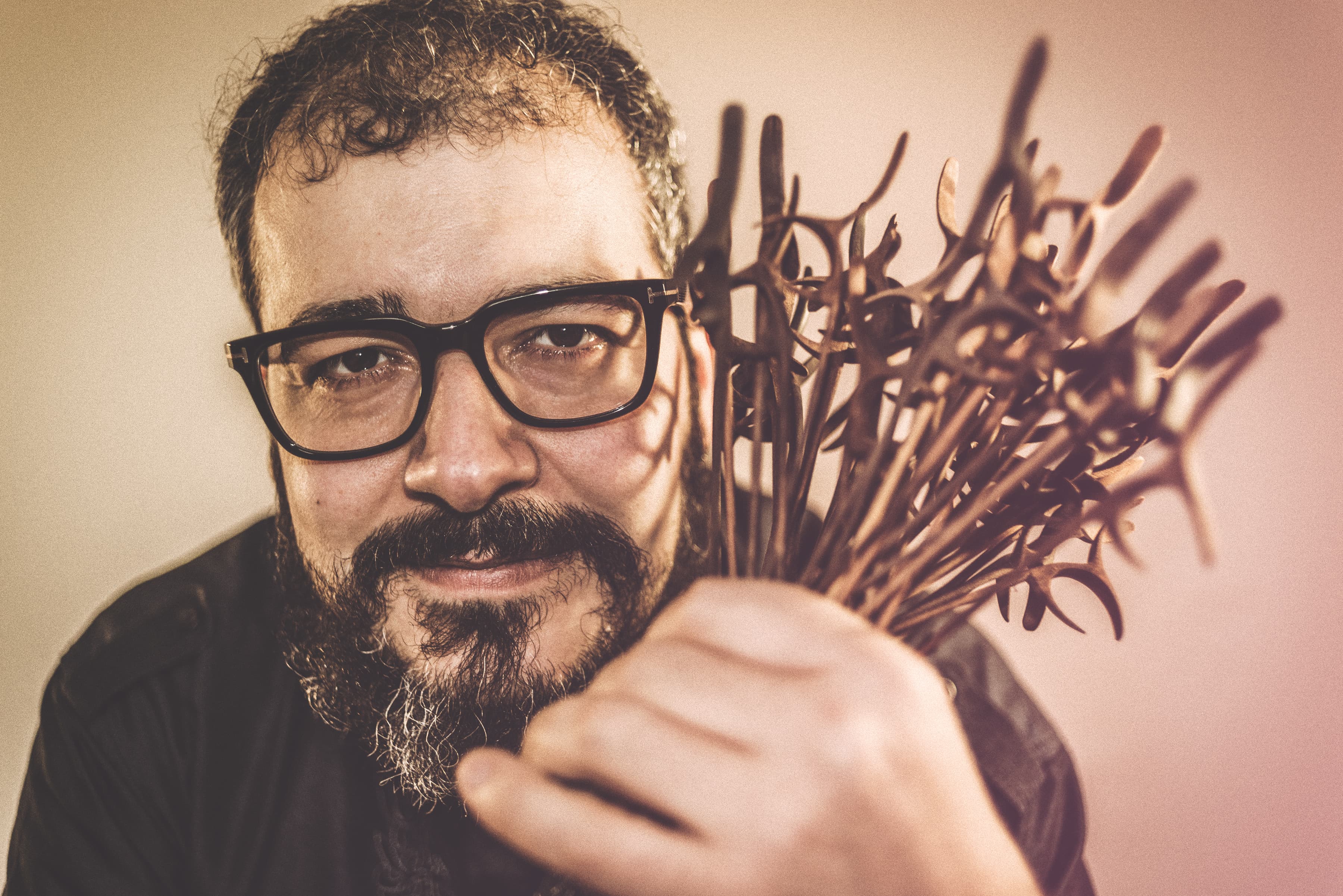 Man with dark black glasses holding flowers close to face