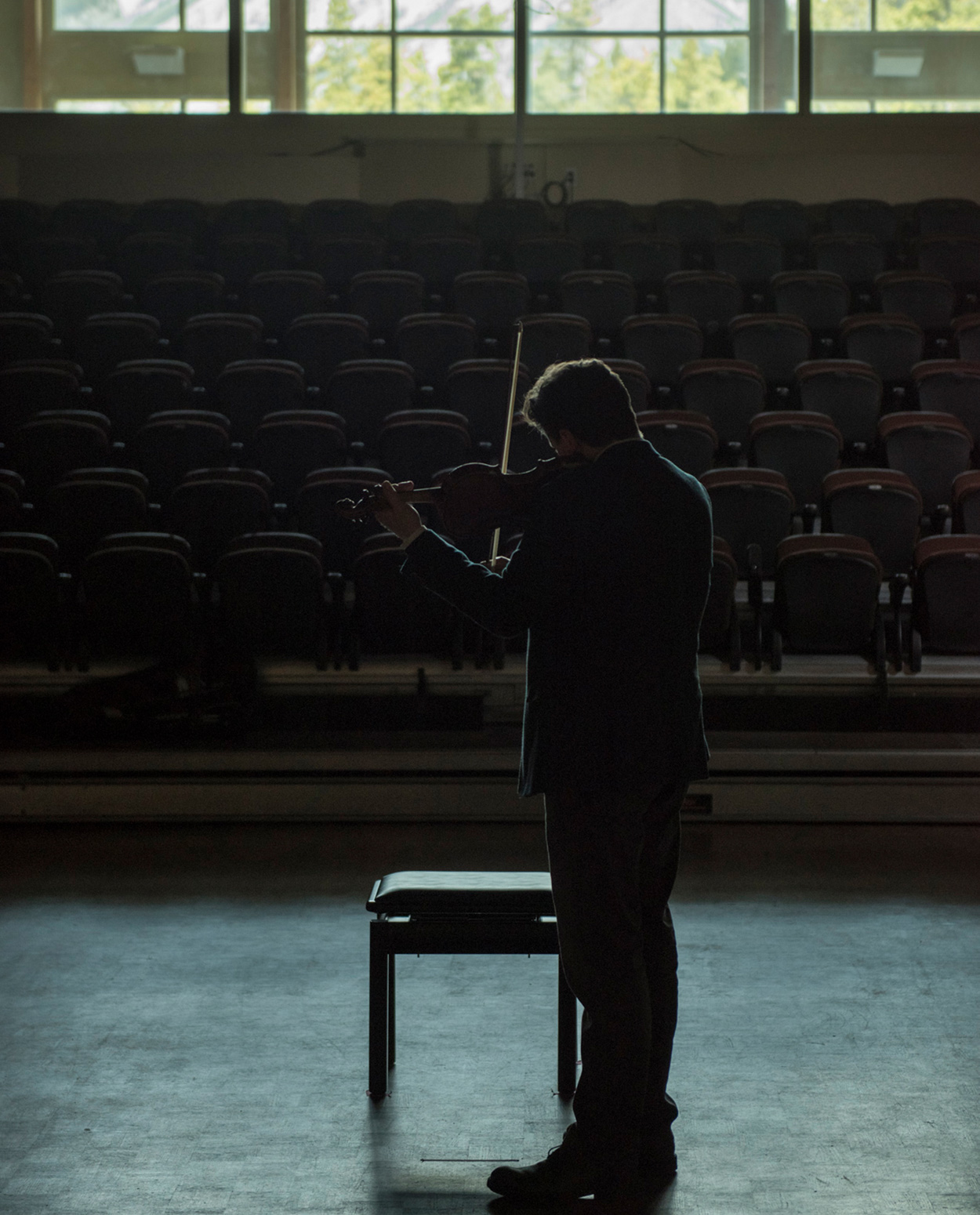 Solo Violinist on a darkly lit stage of an empty theatre. 