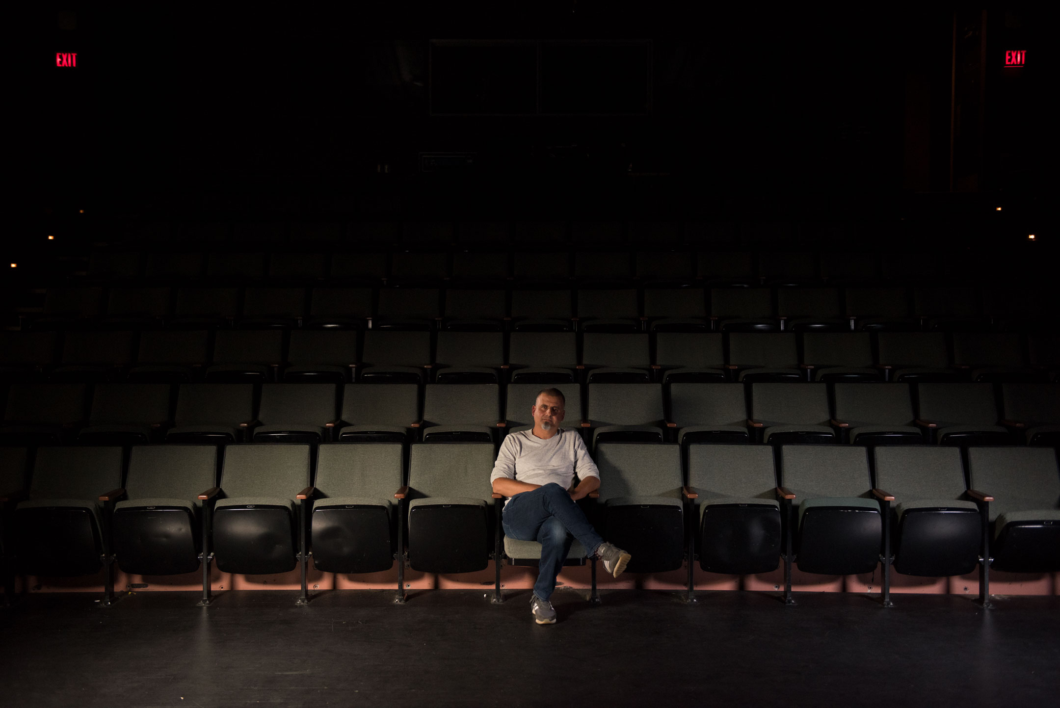 Marcus Youssef sitting in a dark theatre. 