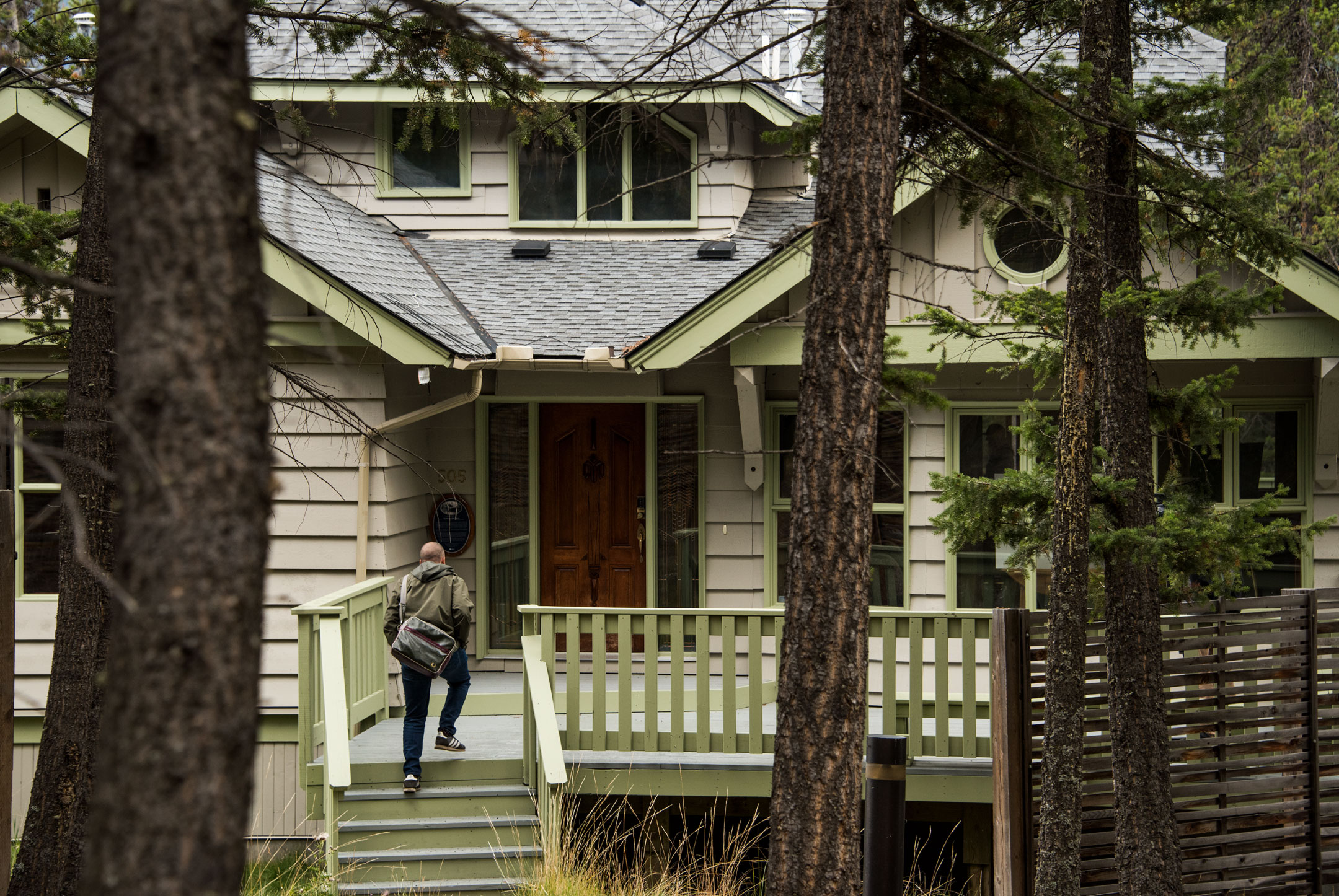 Man walking into a house in the woods.