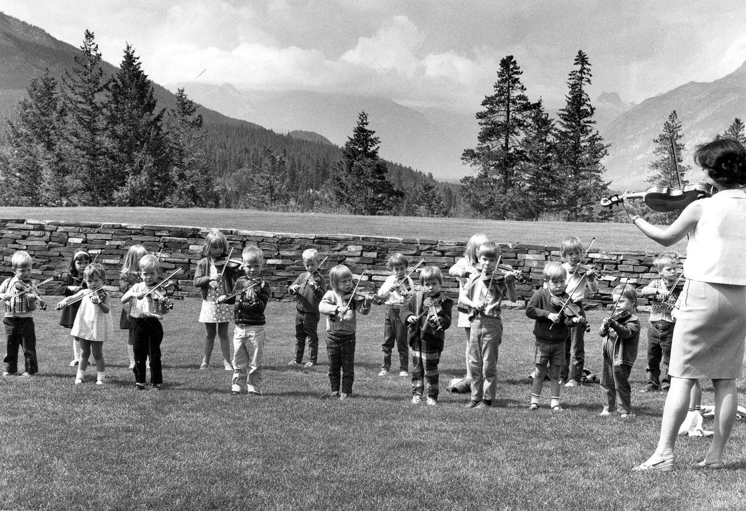 Oike-Wong is pictured here teaching a violin lesson to students on the lawn in front of our Donald Cameron Hall, overloo