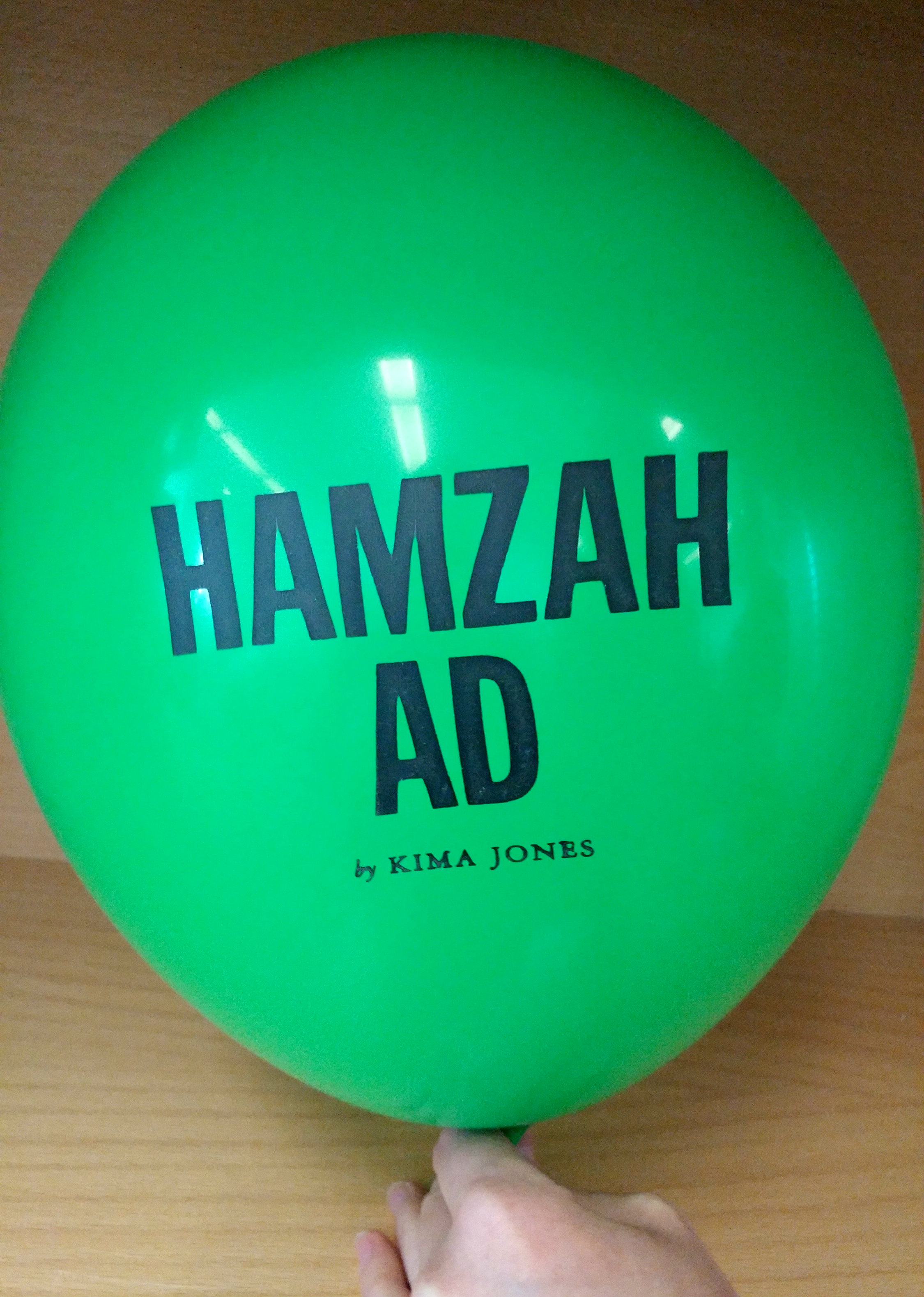 A green balloon inflated with the text, "Hamzah Ad by Kima Jones" printed on it. 