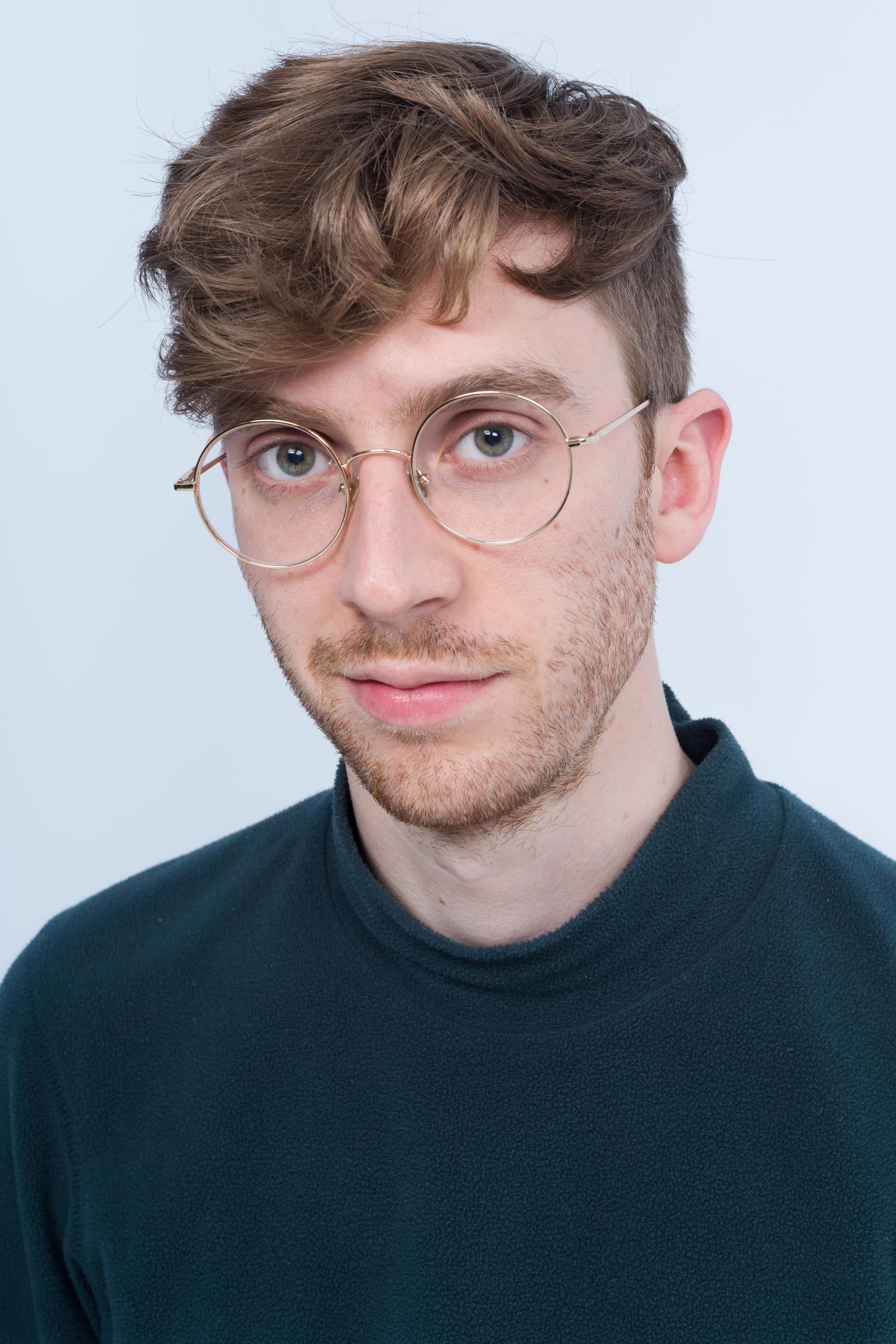 Man with short curly hair and glasses looking straight at camera