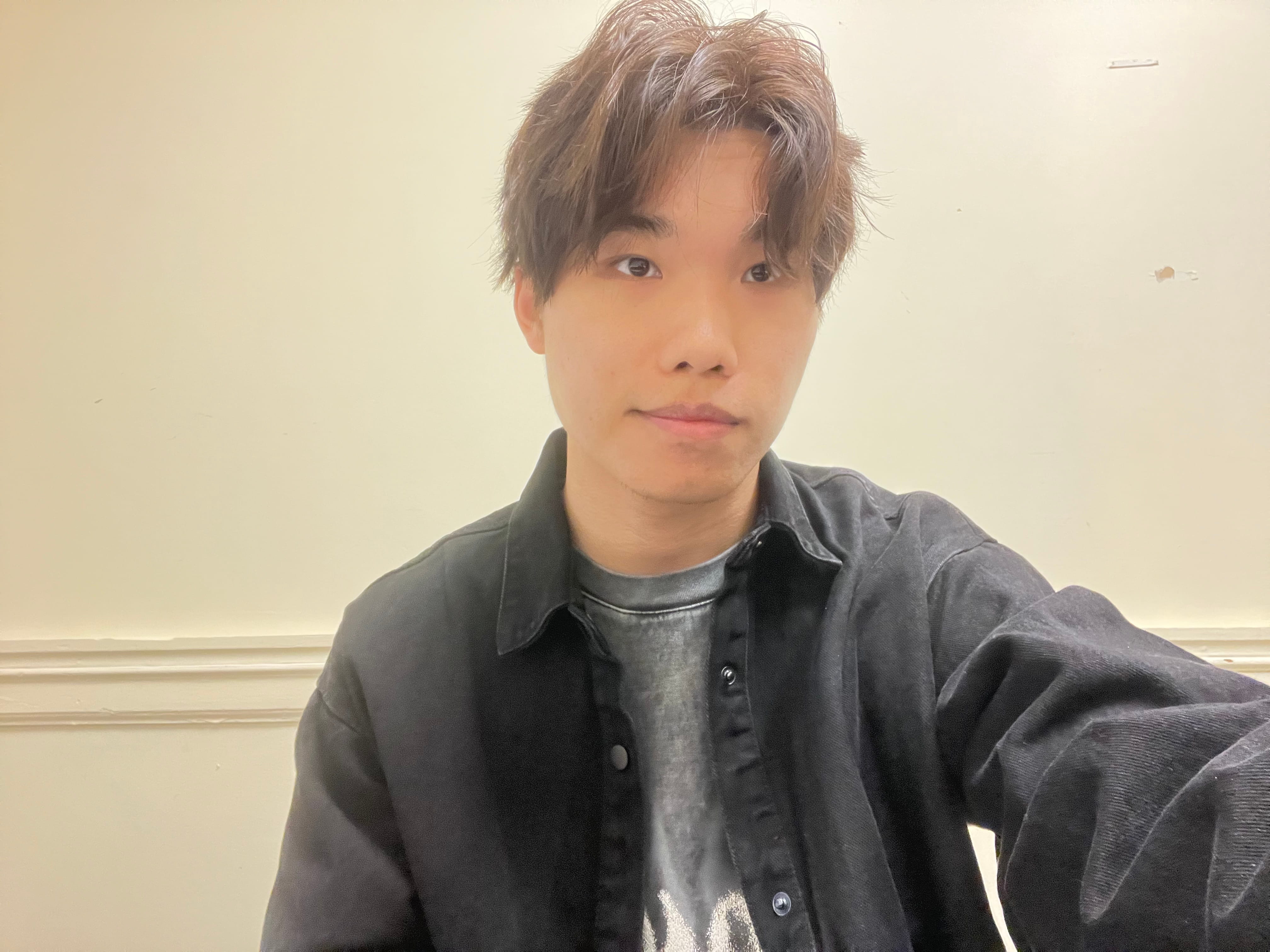 Selfie shot of a young man in casual dress smiling lightly at the camera