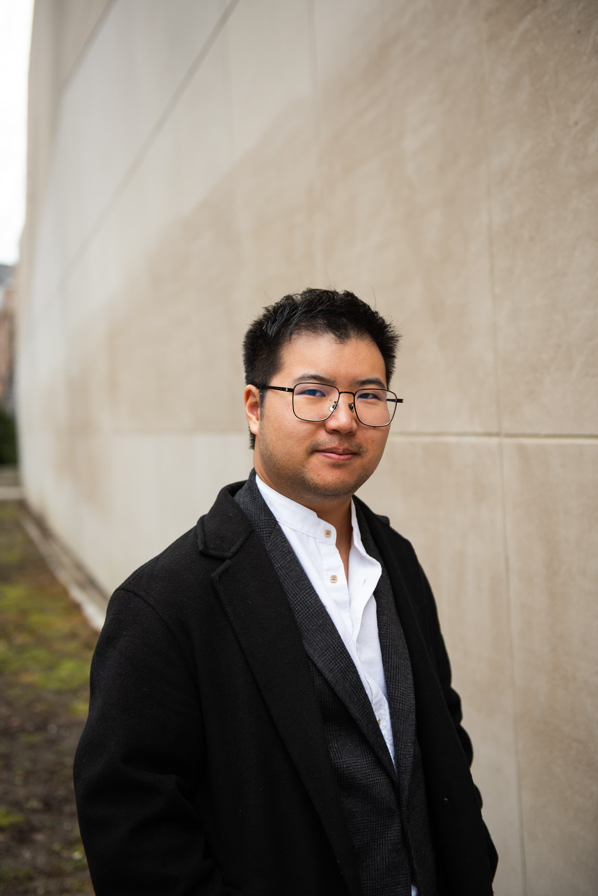 Man in black suit with eye glasses looking directly at the camera