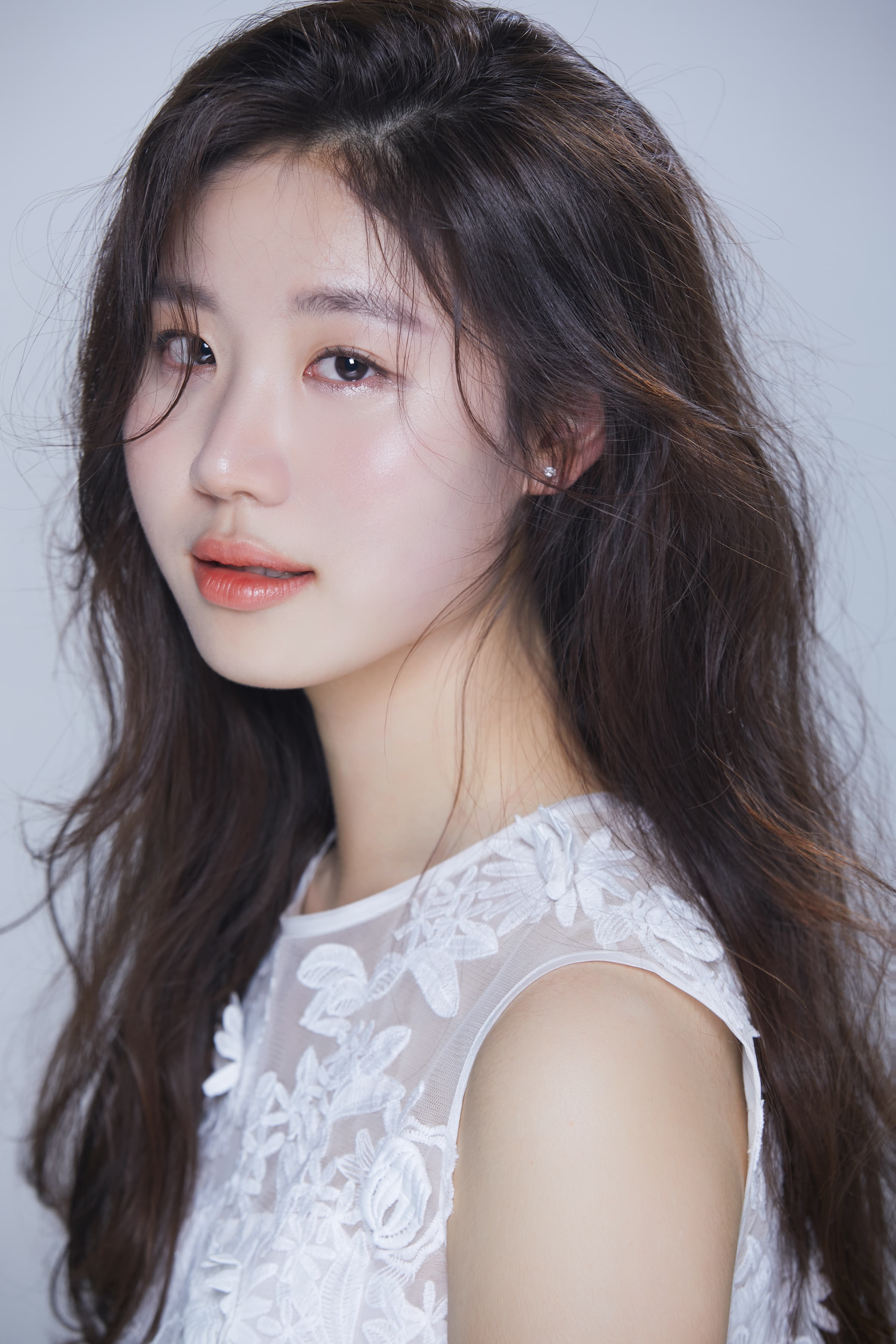 Woman with long dark hair and white shirt looking at camera