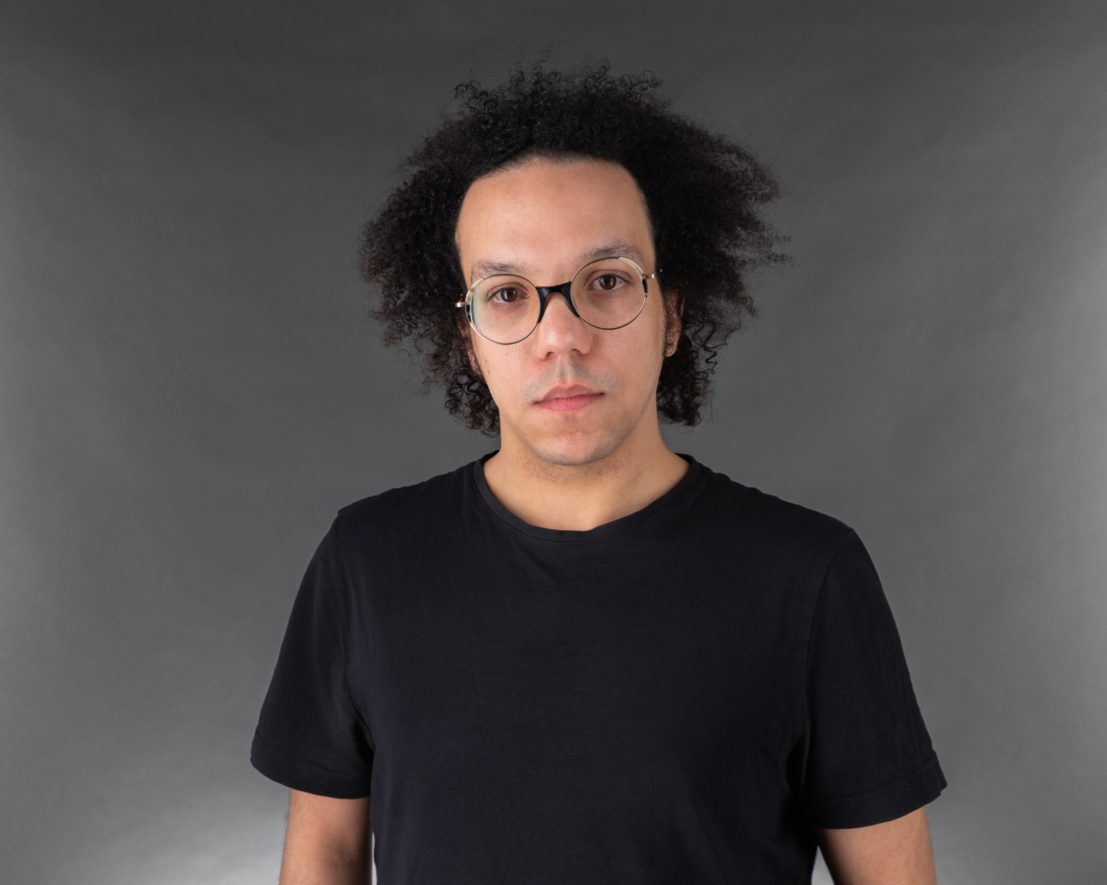 Man wearing a dark t-shirt and glasses staring at the camera