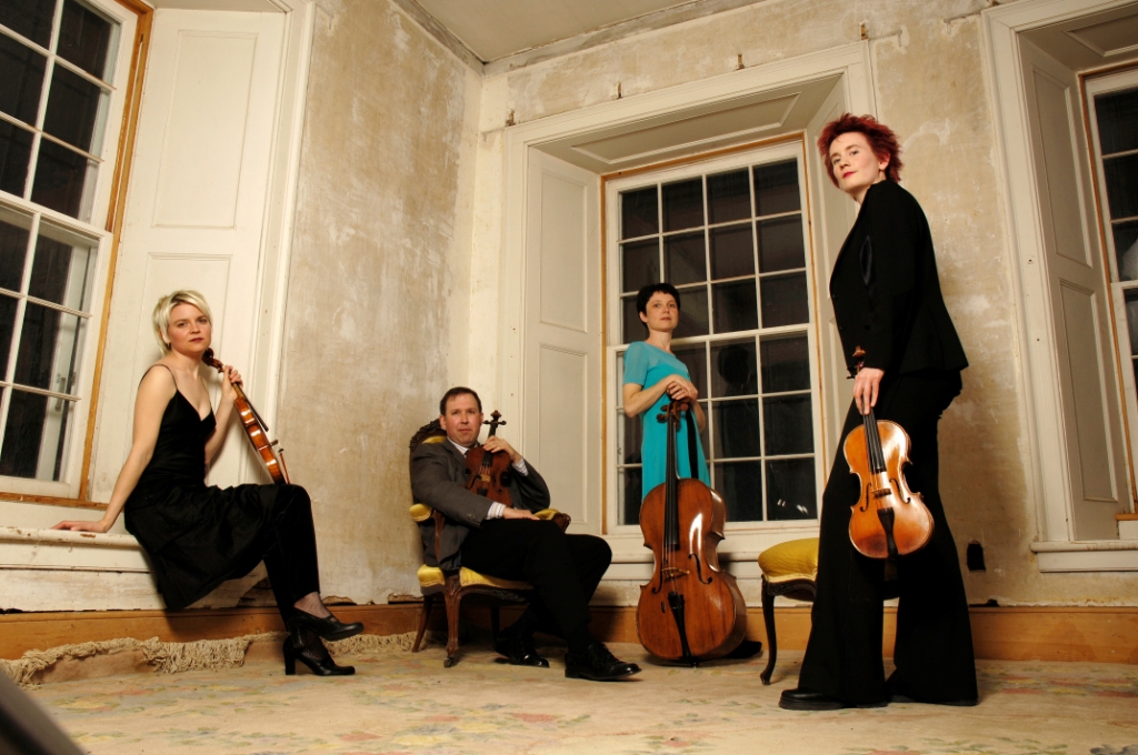 The Eybler Quartet, a Banff Centre Faculty Quartet, poses in front of a series of windows set into an inside corner of a