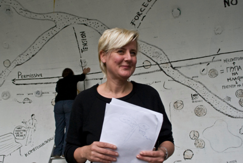 Jeanne van Heeswijk standing in front of an artistically styled map.