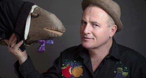 Norman Foote holds a puppet facing himself.