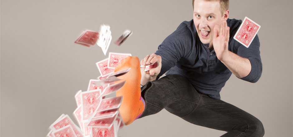 Wes Barker launches cards through the air over an outstretched jump-kick.