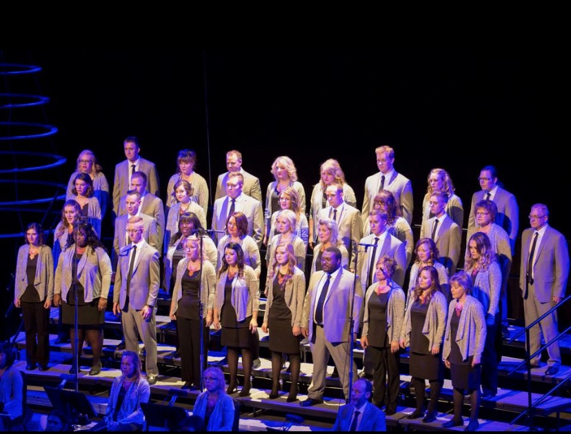 The New West Symphony & Chorus has their choral group in black clothes and beige blazers sings on stage.