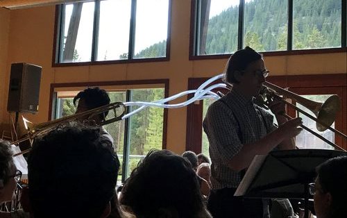 Displaying experimental music two trombonists perform with their instruments connected by clear plastic hosing.  