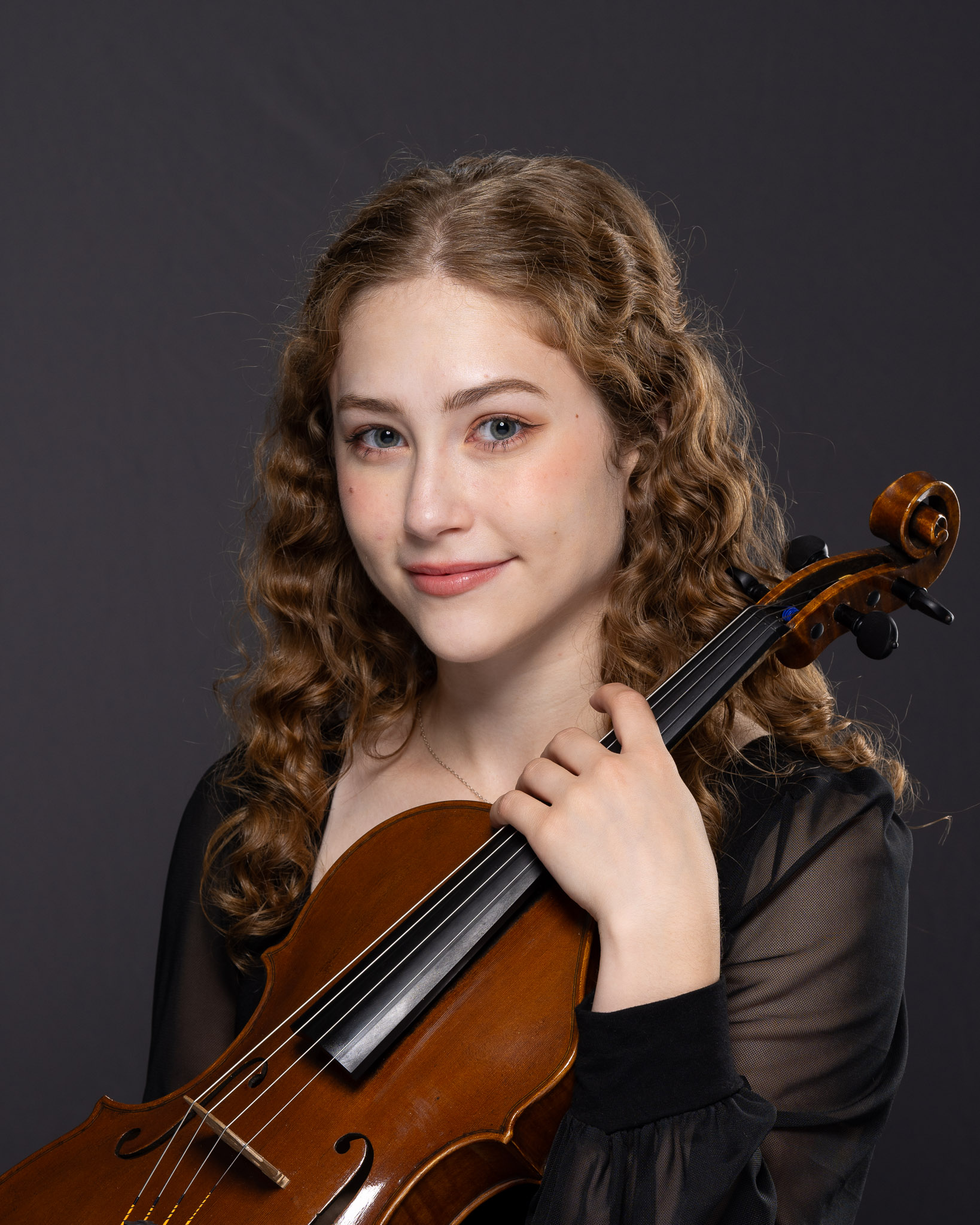 Woman holding violin and smiling at camera