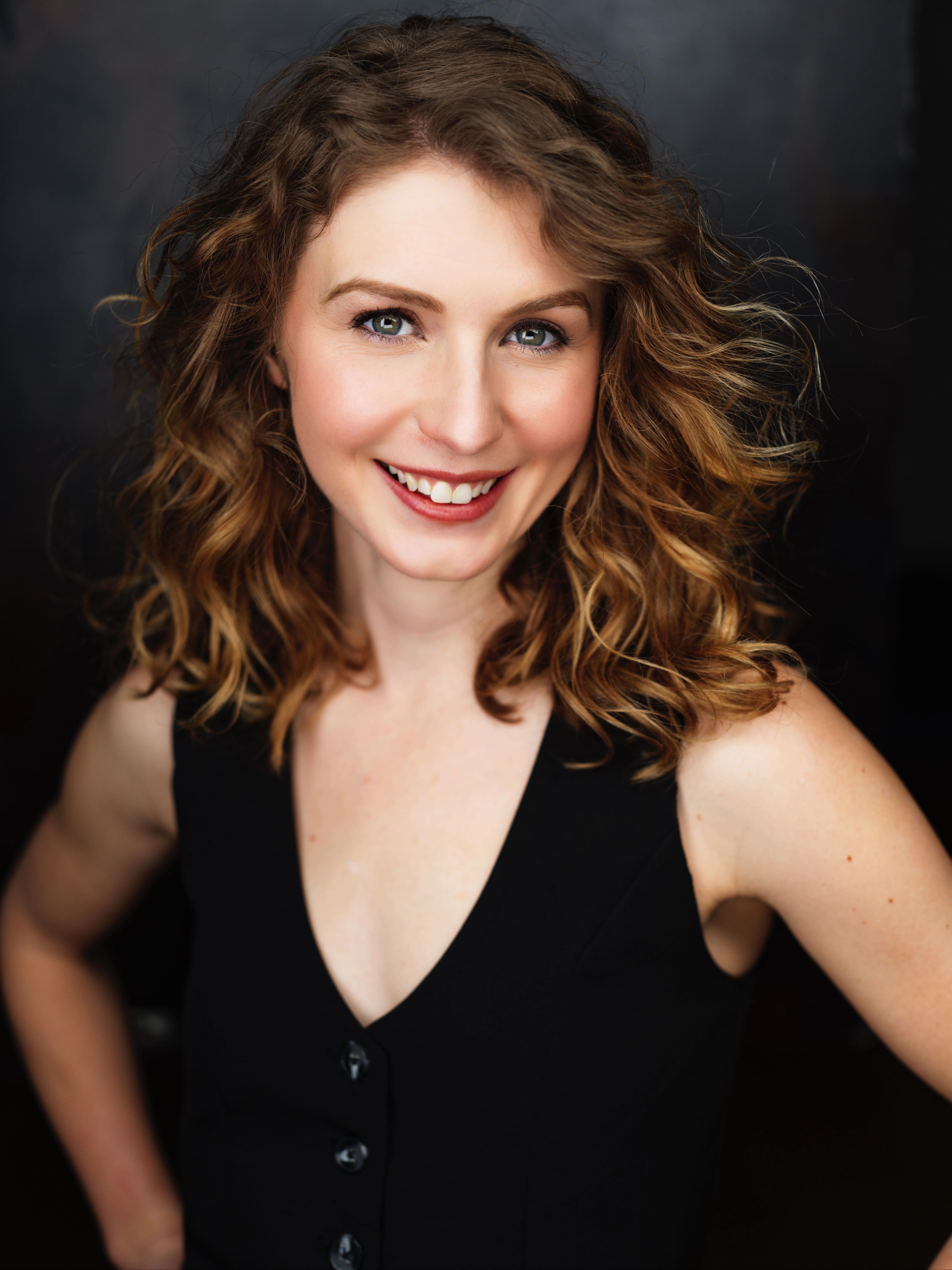 Woman standing with hands on hips and smiling directly at camera