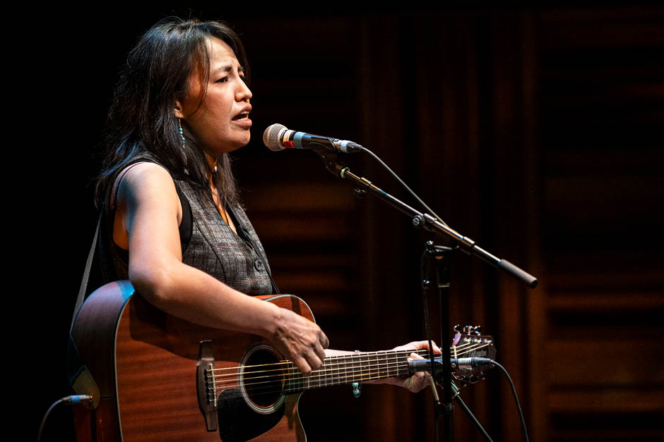 A singer is playing the guitar and singing into a microphone