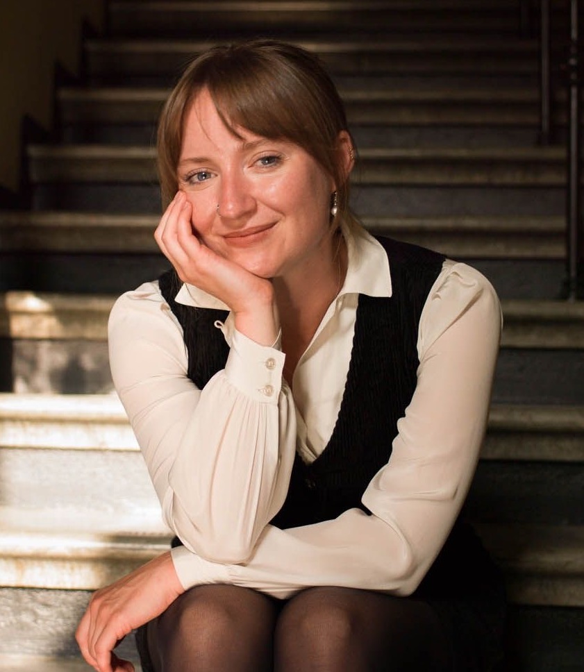 Woman in a relaxed pose smiling directly at the camera