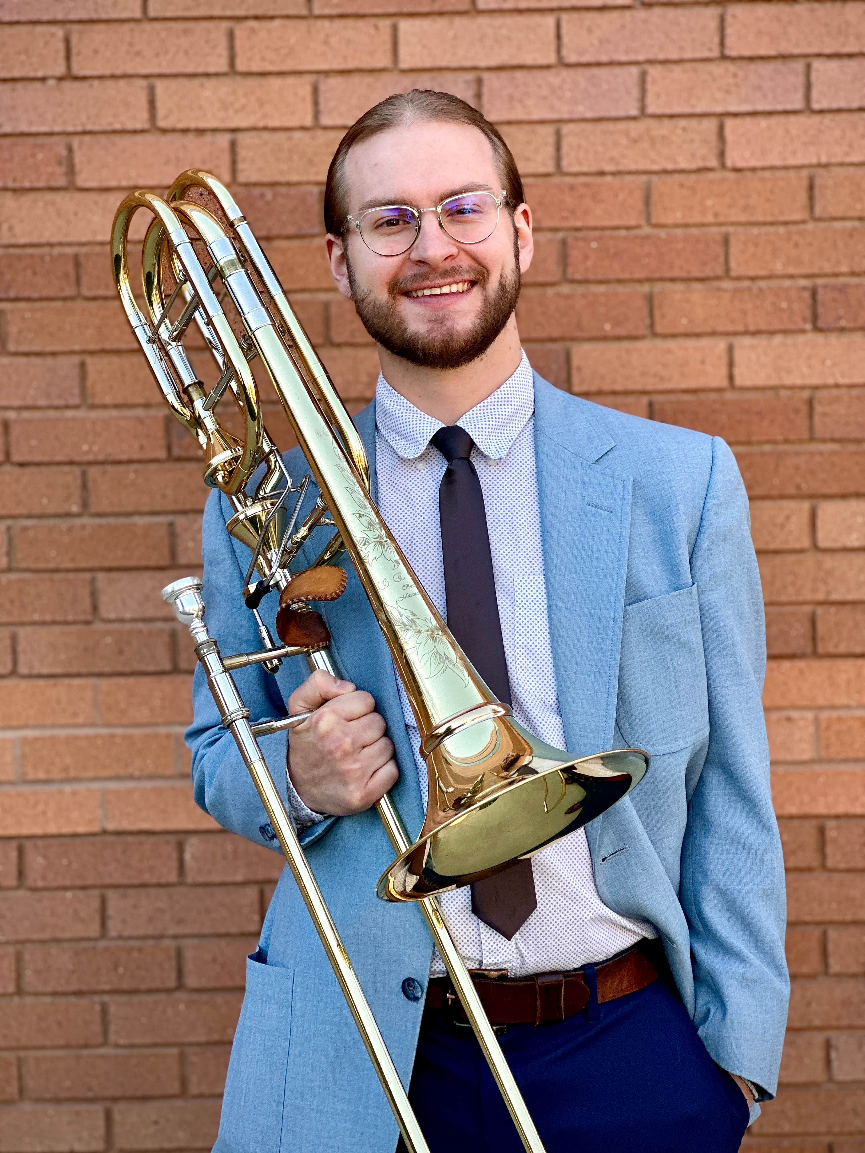 Man in suit holding trombone and smiling at camera