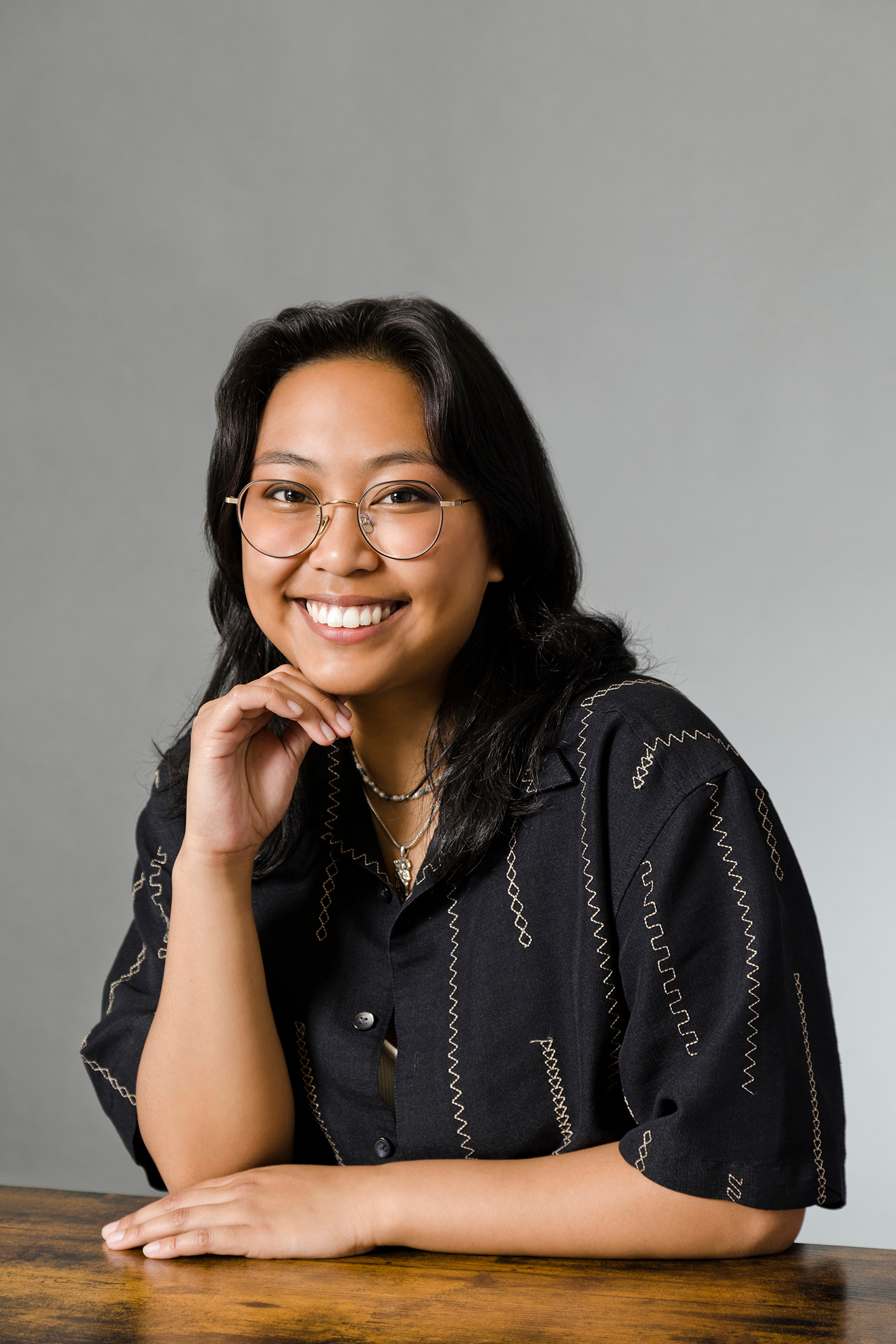 Woman sitting behind desk smiling broadly at the camera