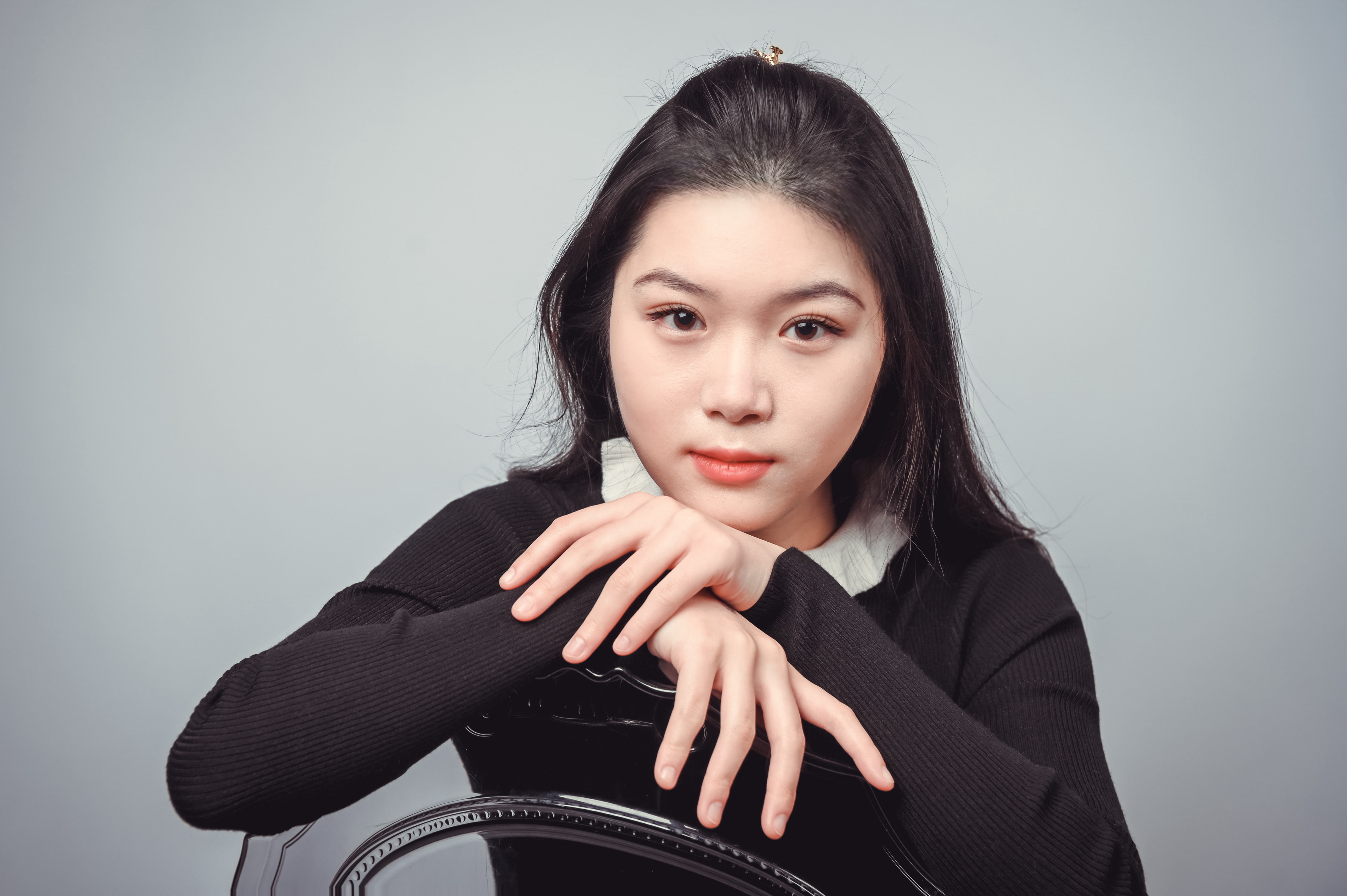 Woman sitting backwards on a chair in a black sweater looking directly at the camera