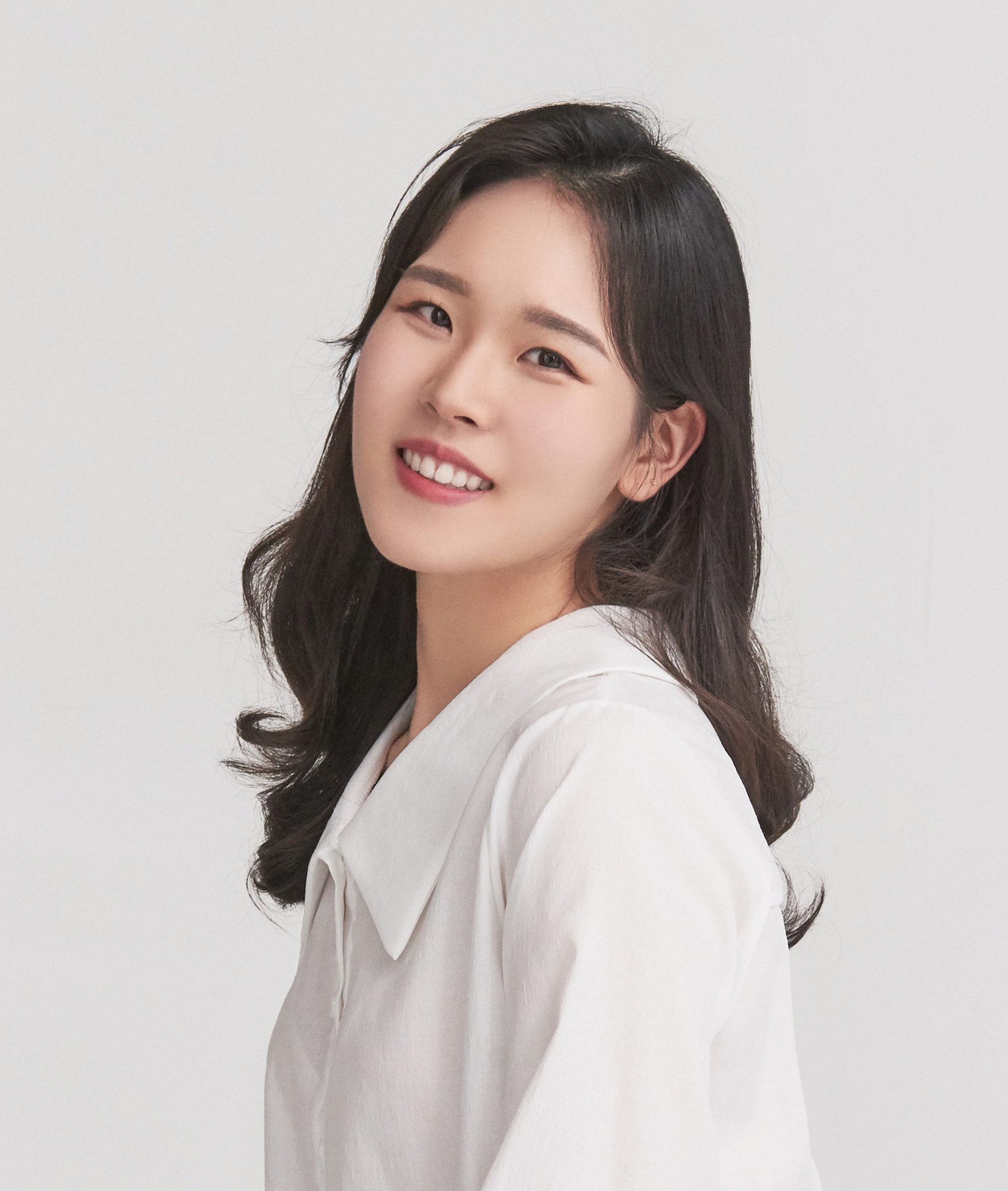 Woman with long black hair smiling at camera with head tilted back