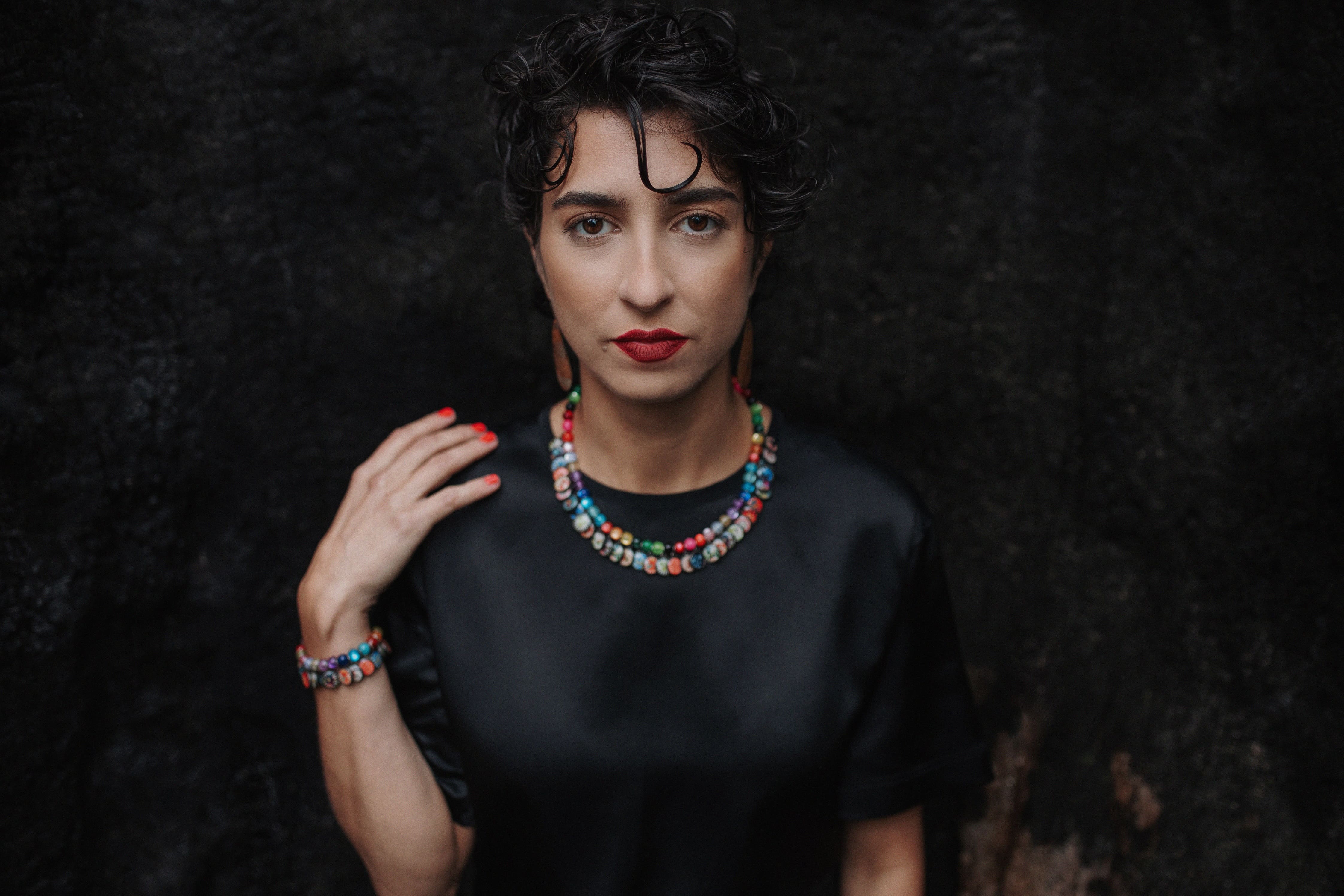 Person in black top and colourful necklace looking directly at the camera