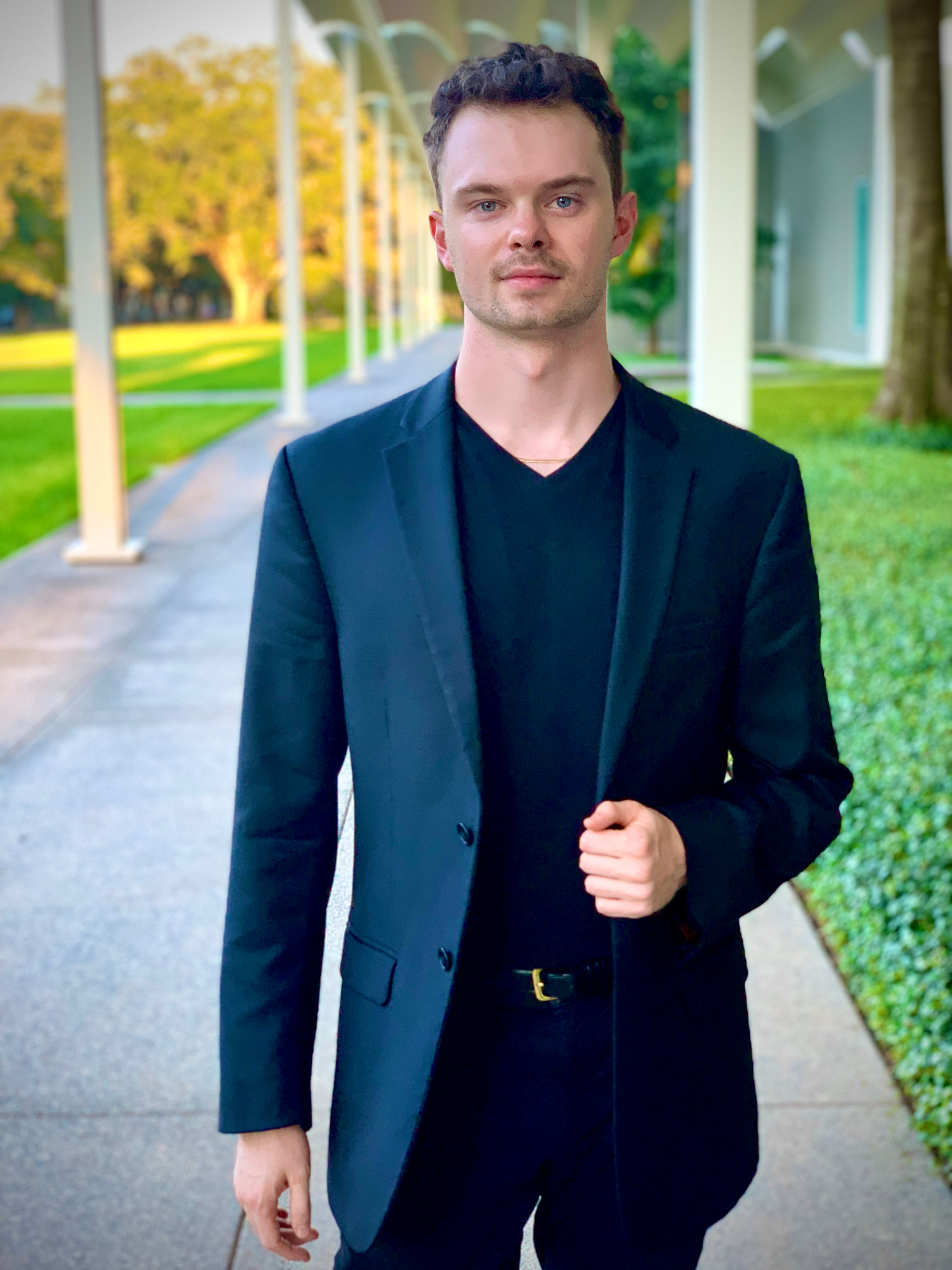Man outside on a walkway in a dark suit staring directly at camera