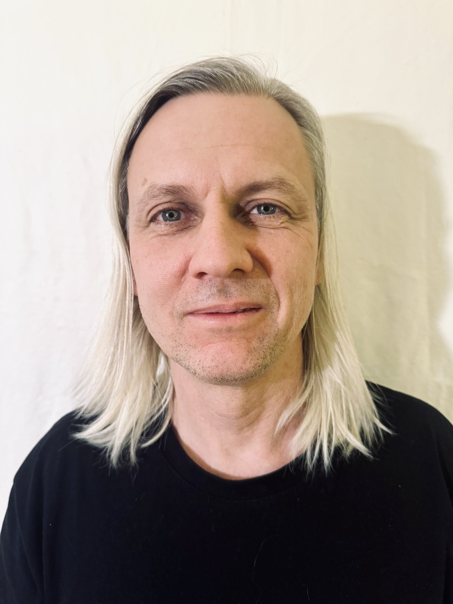 Person with blonde shoulder length hair looking directly at the camera