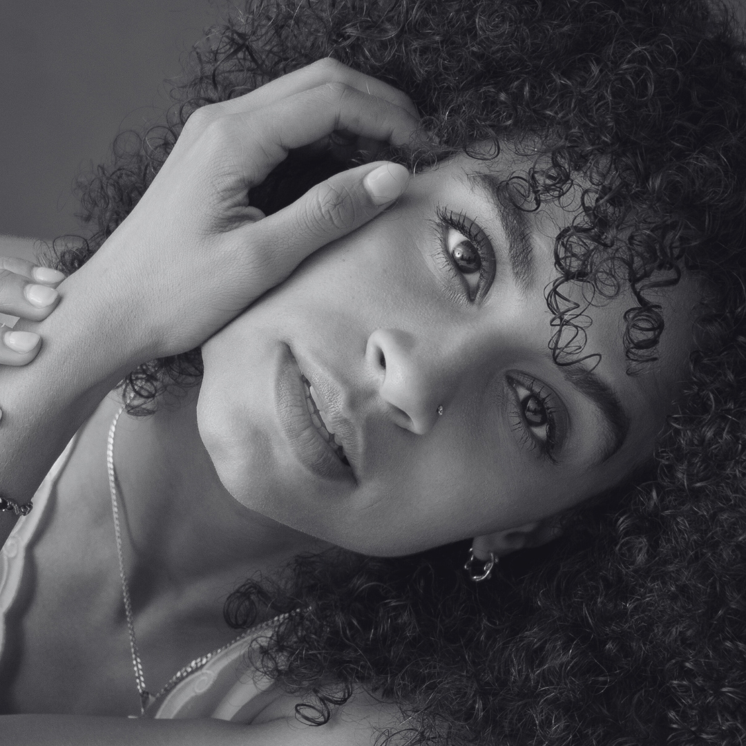 Black and white photo of woman with hand on side of face and head tilted to side