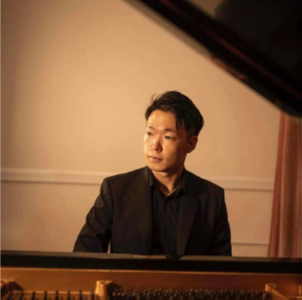 Man sitting behind piano looking off camera