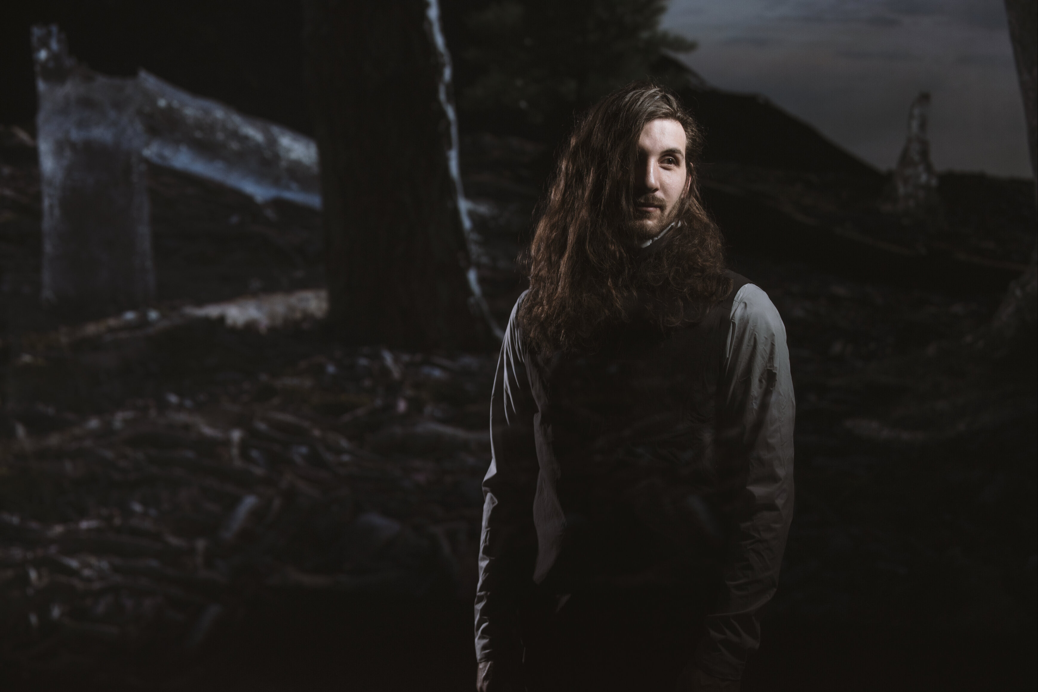 Man standing in front of fence in dark photo where only face is light