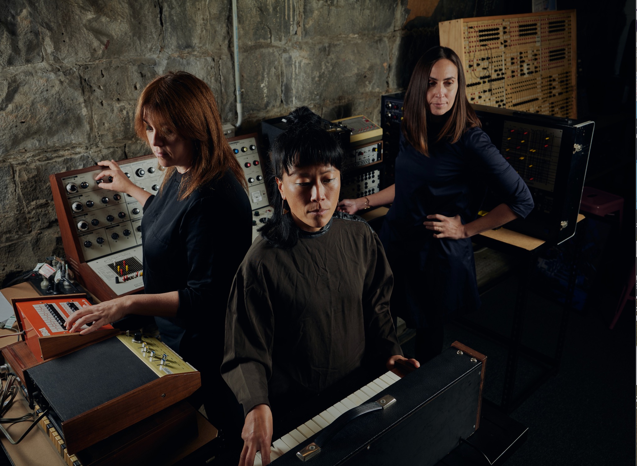 3 people standing in a circle with instruments surrounding them