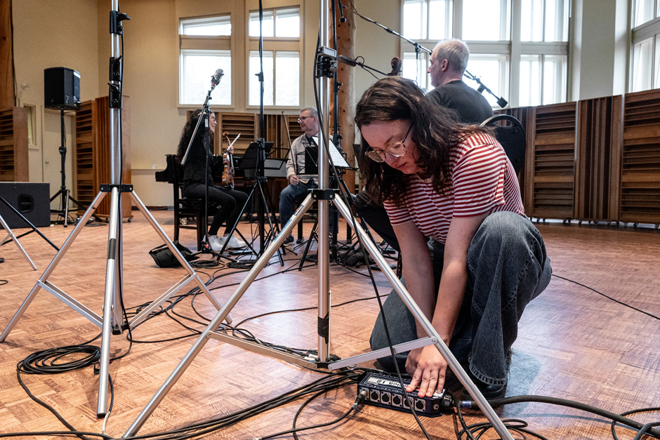 An audio engineer is kneeling on the floor to adjust audio cables