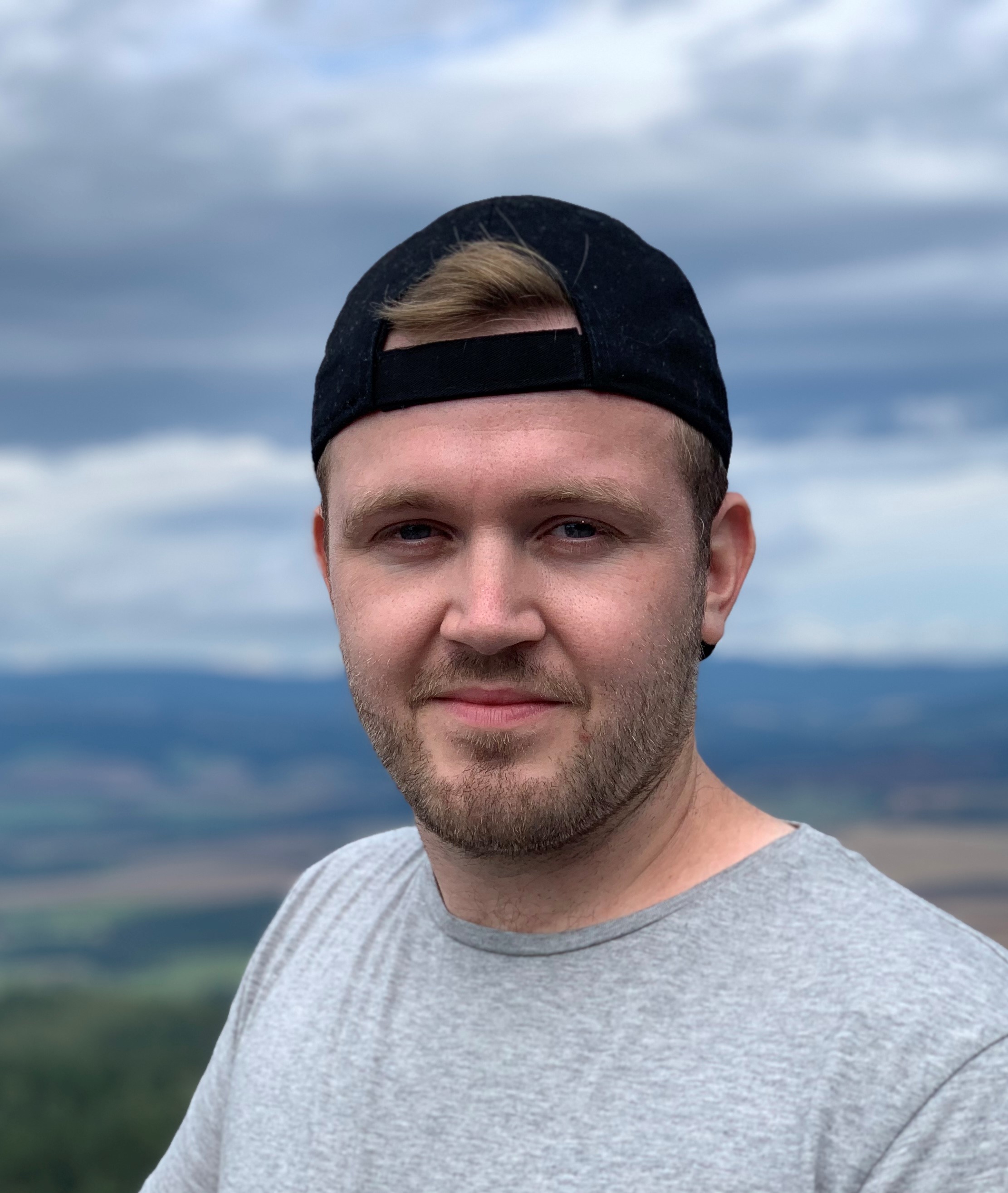 Man in a casual t-shirt and backwards baseball hat on a hill