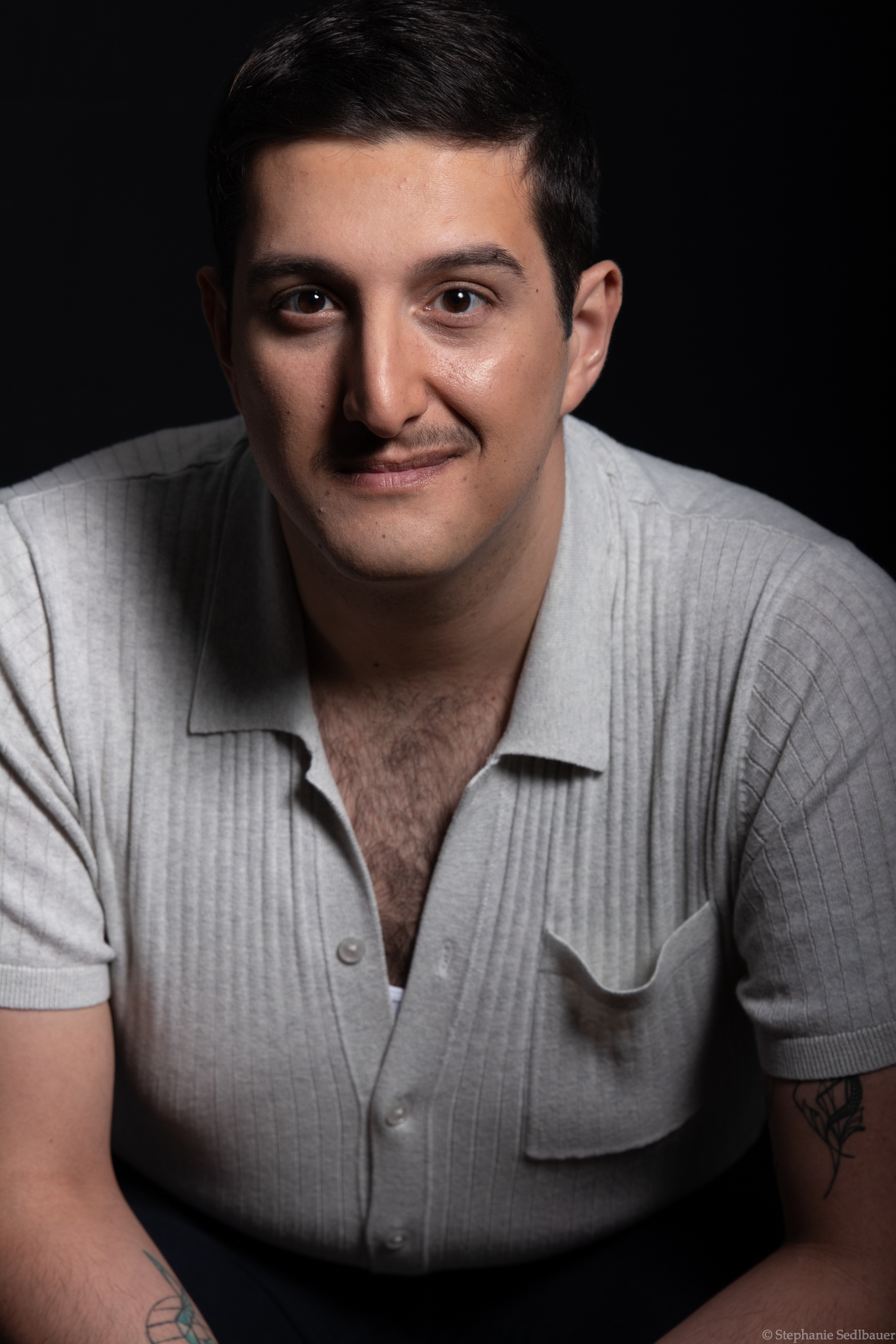 Man sitting leaning close to the camera with slight smile