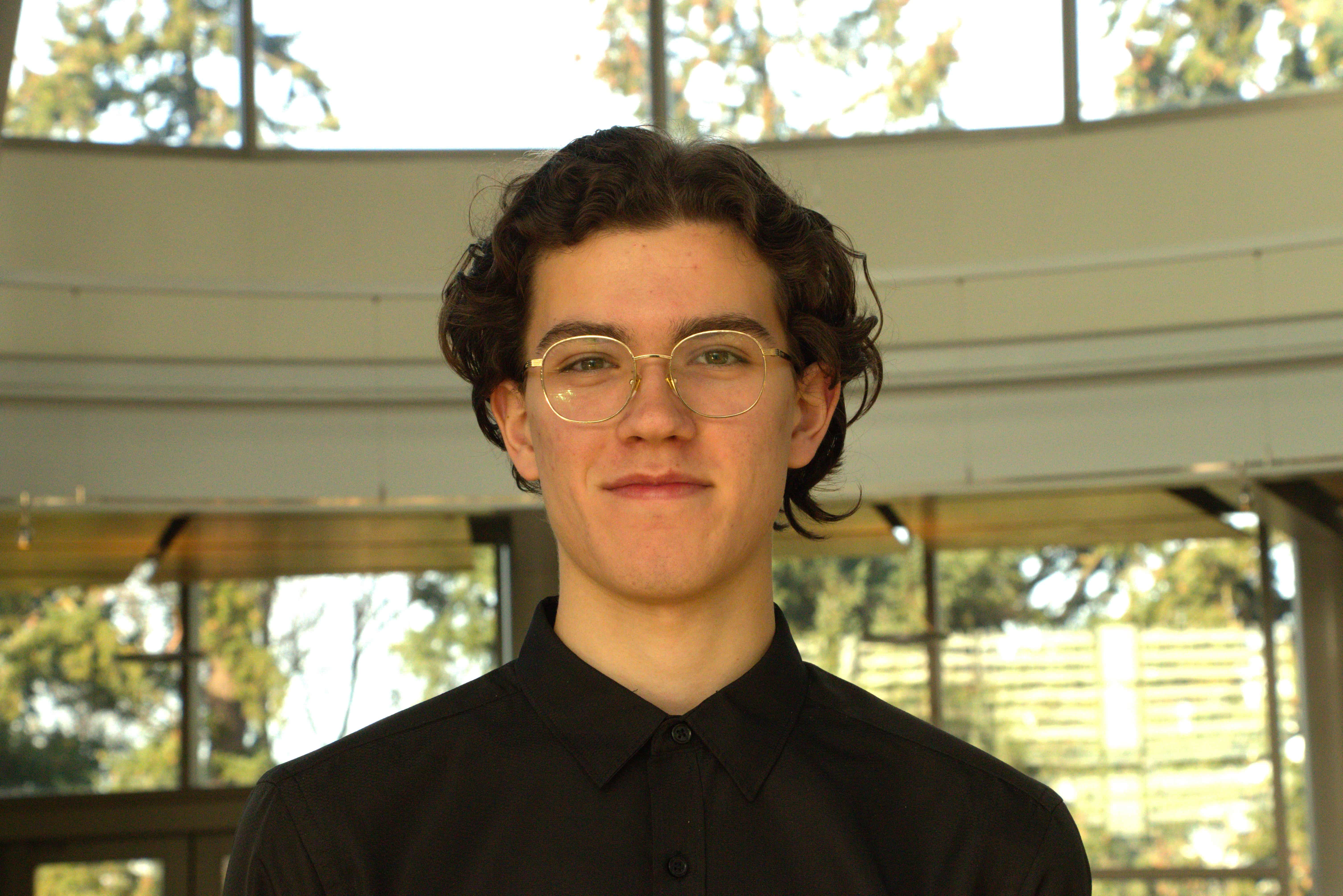 Man wearing black shirt and glasses looking at camera