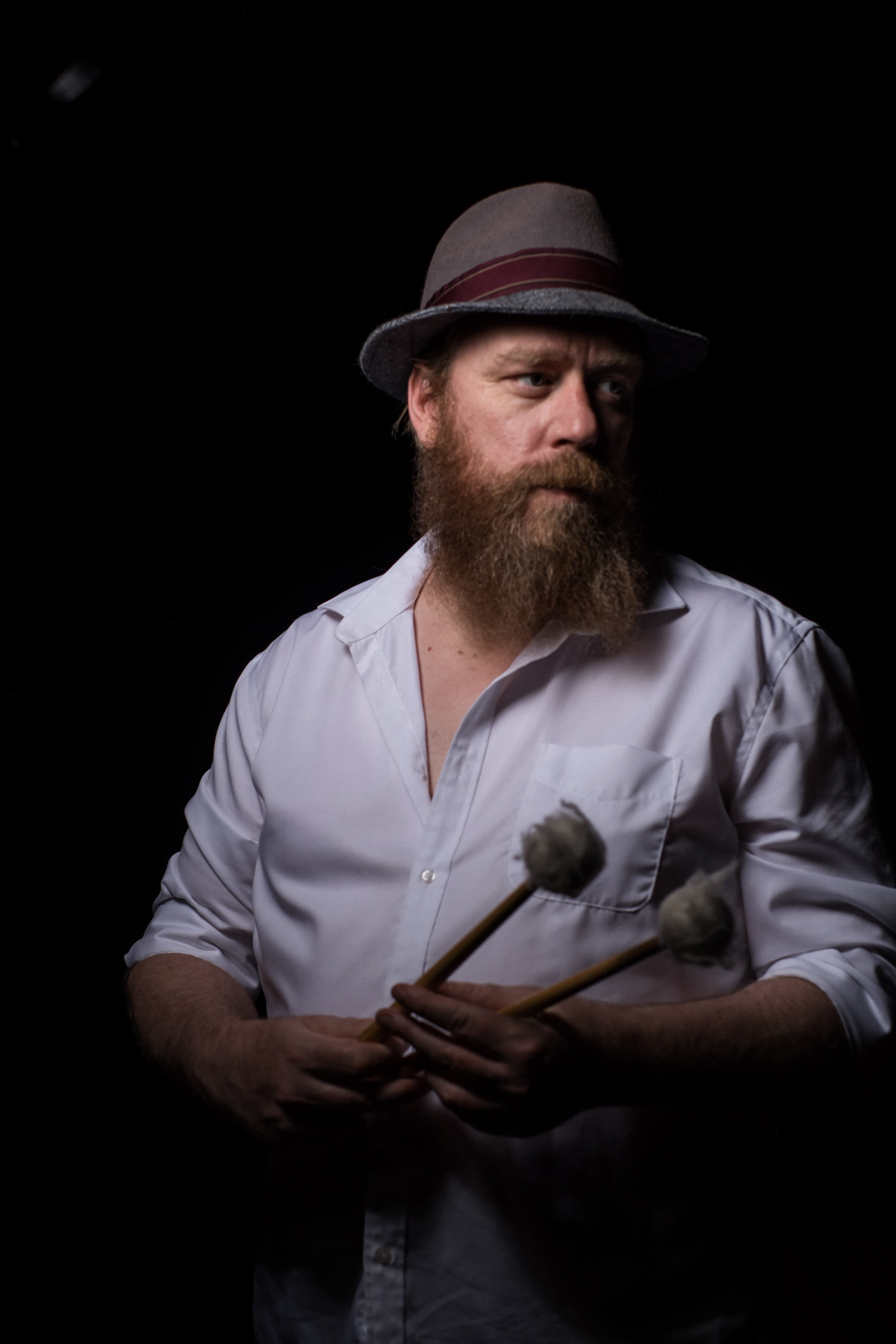 Person wearing hat and wearing a button up shirt looking off to the side