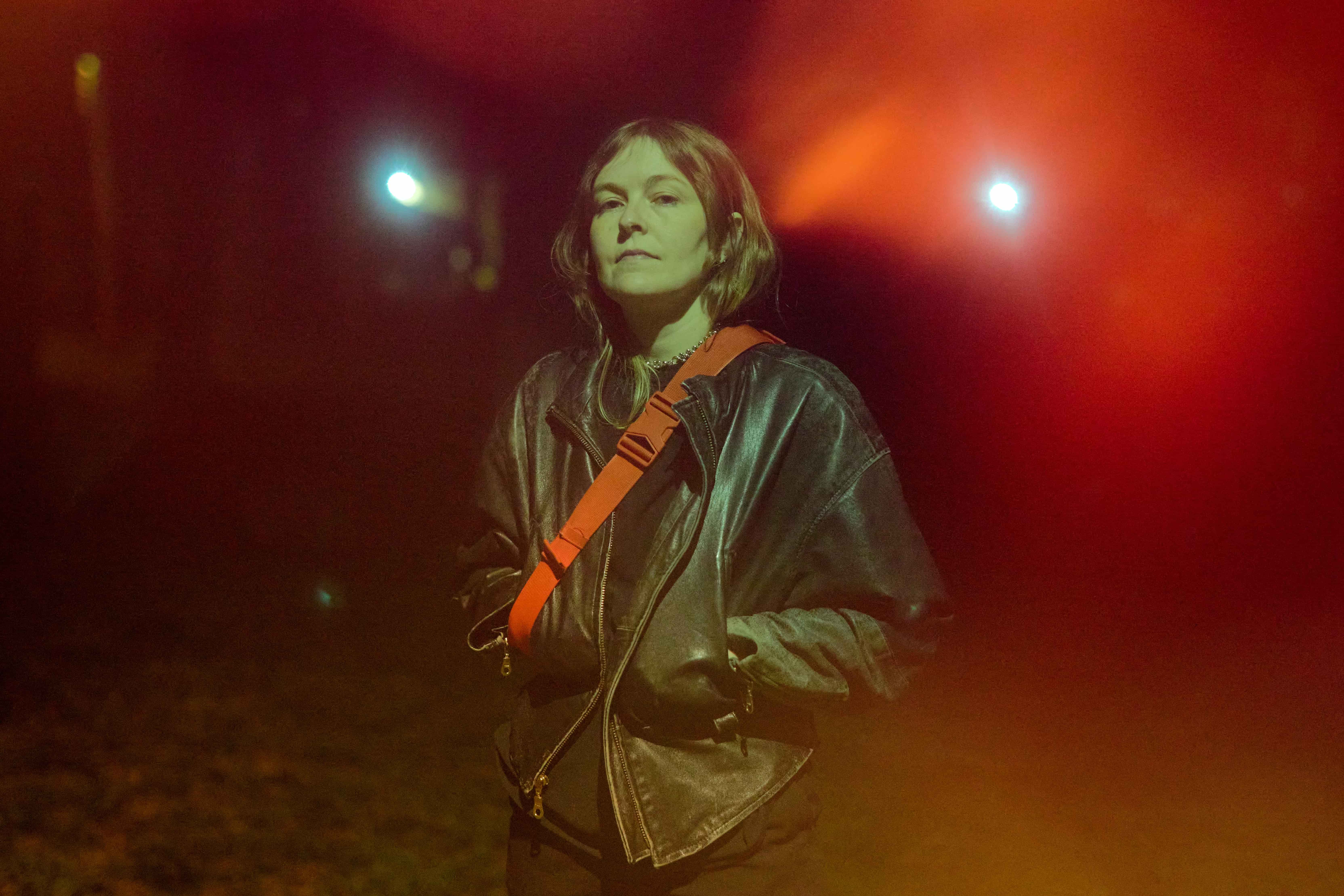 Woman in leather jacket standing in front of lights at night