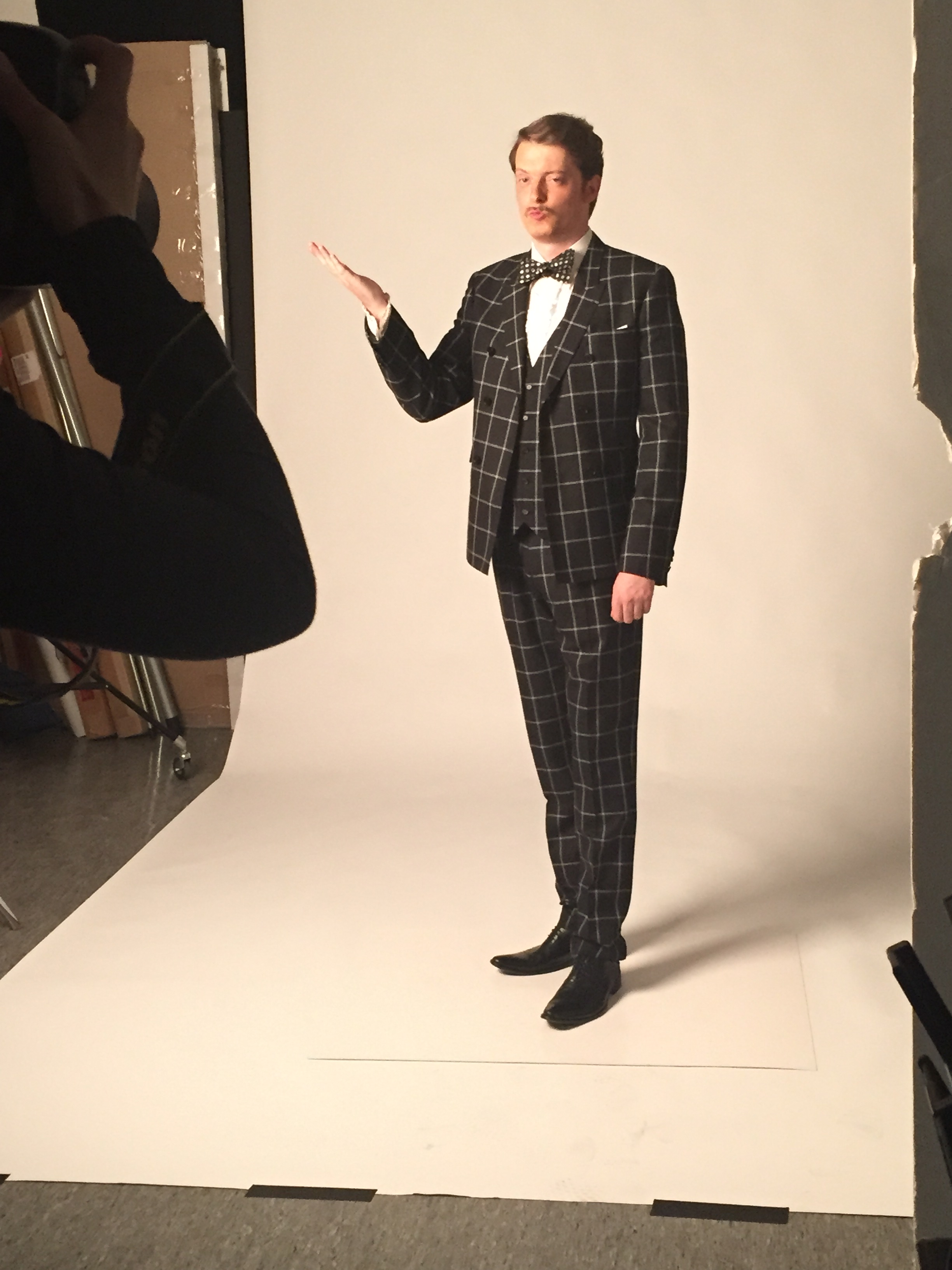 Man in plaid suit poses for camer in photo studio