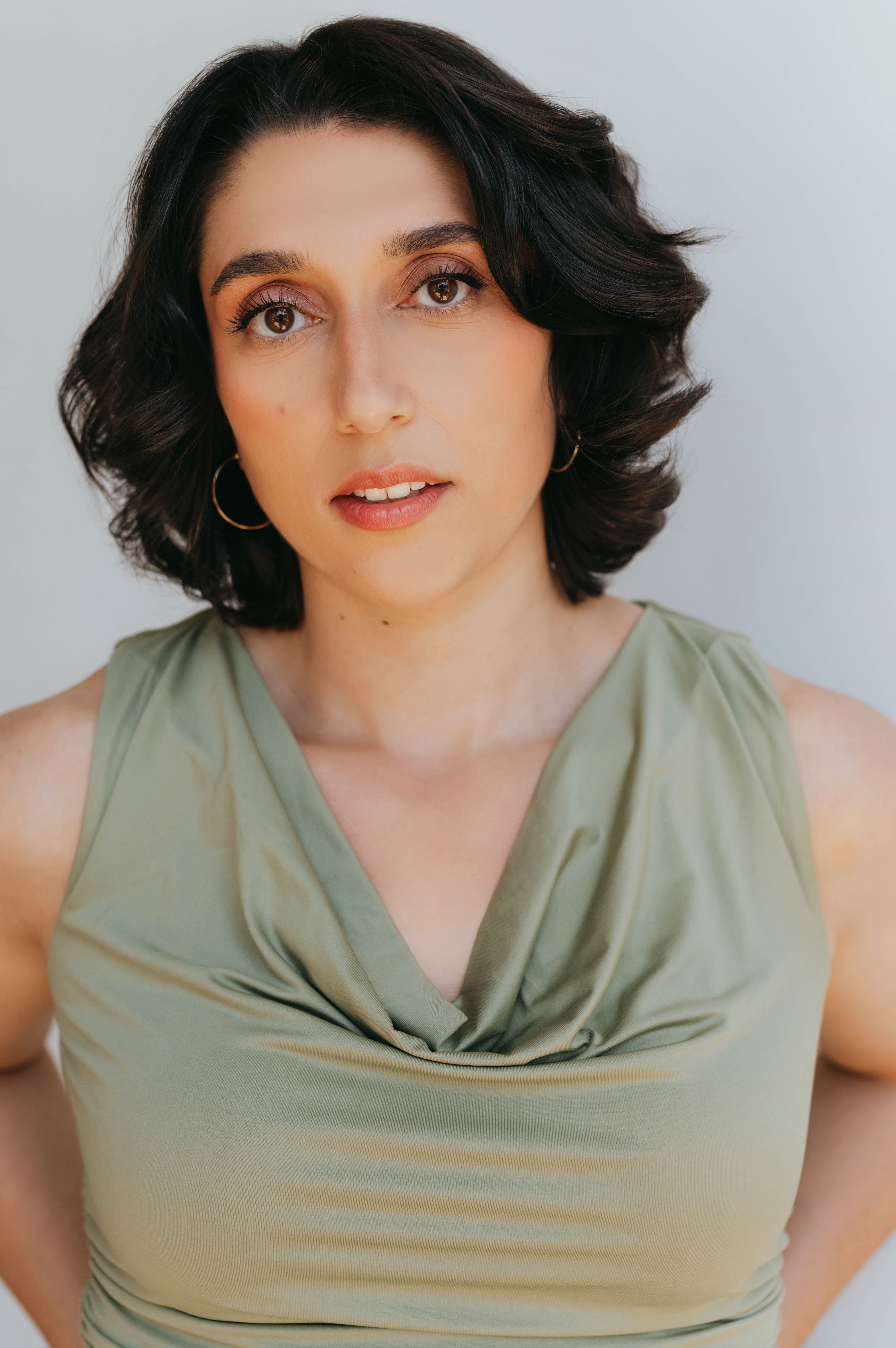 Woman standing with hands behind her back on hips looking directly at the camera