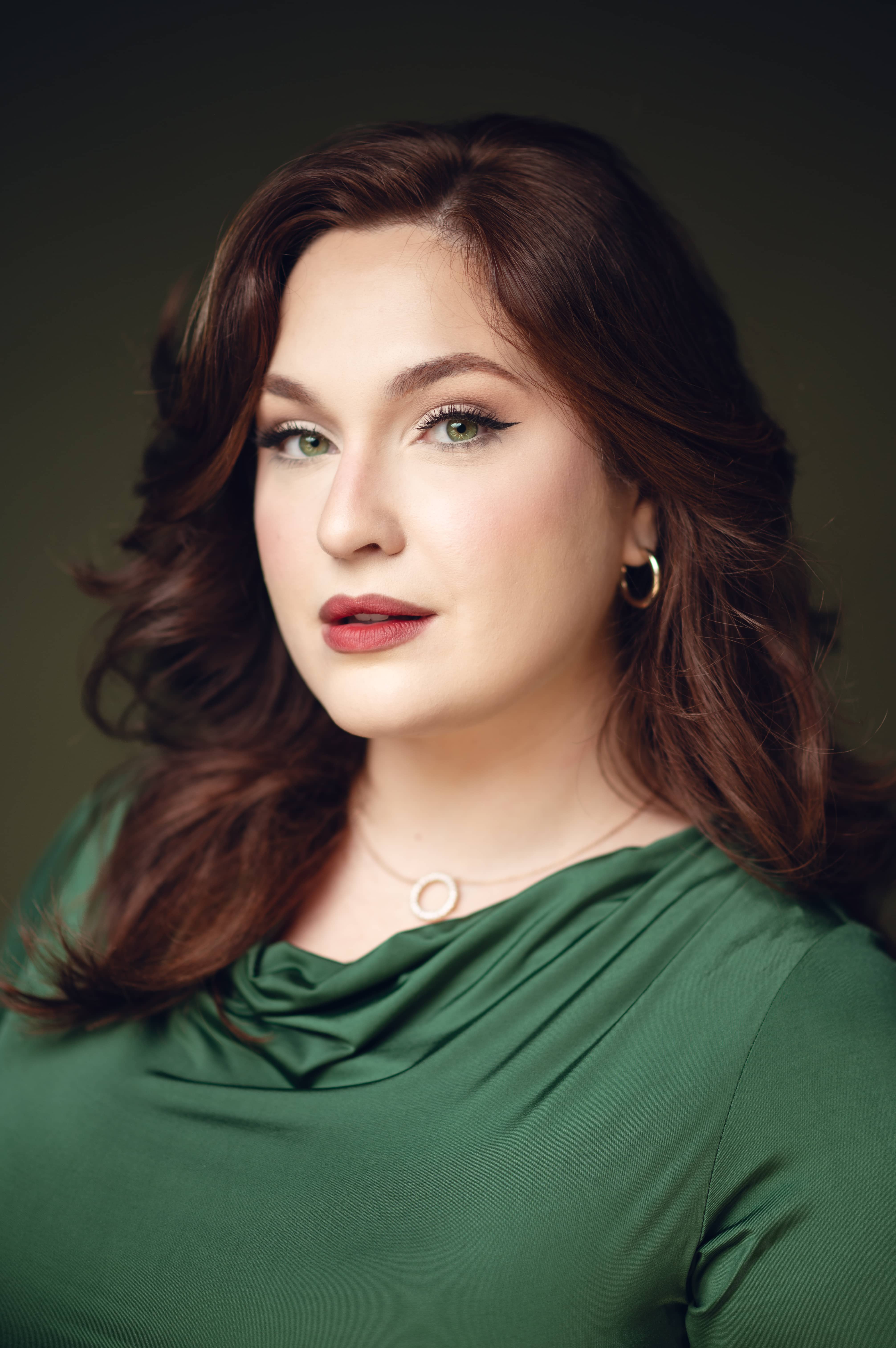 Woman in bright green shirt with red hair staring directly at camera