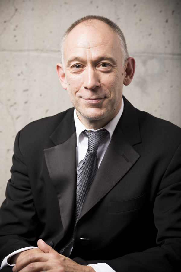 Man smiling lightly at camera wearing suit and tie