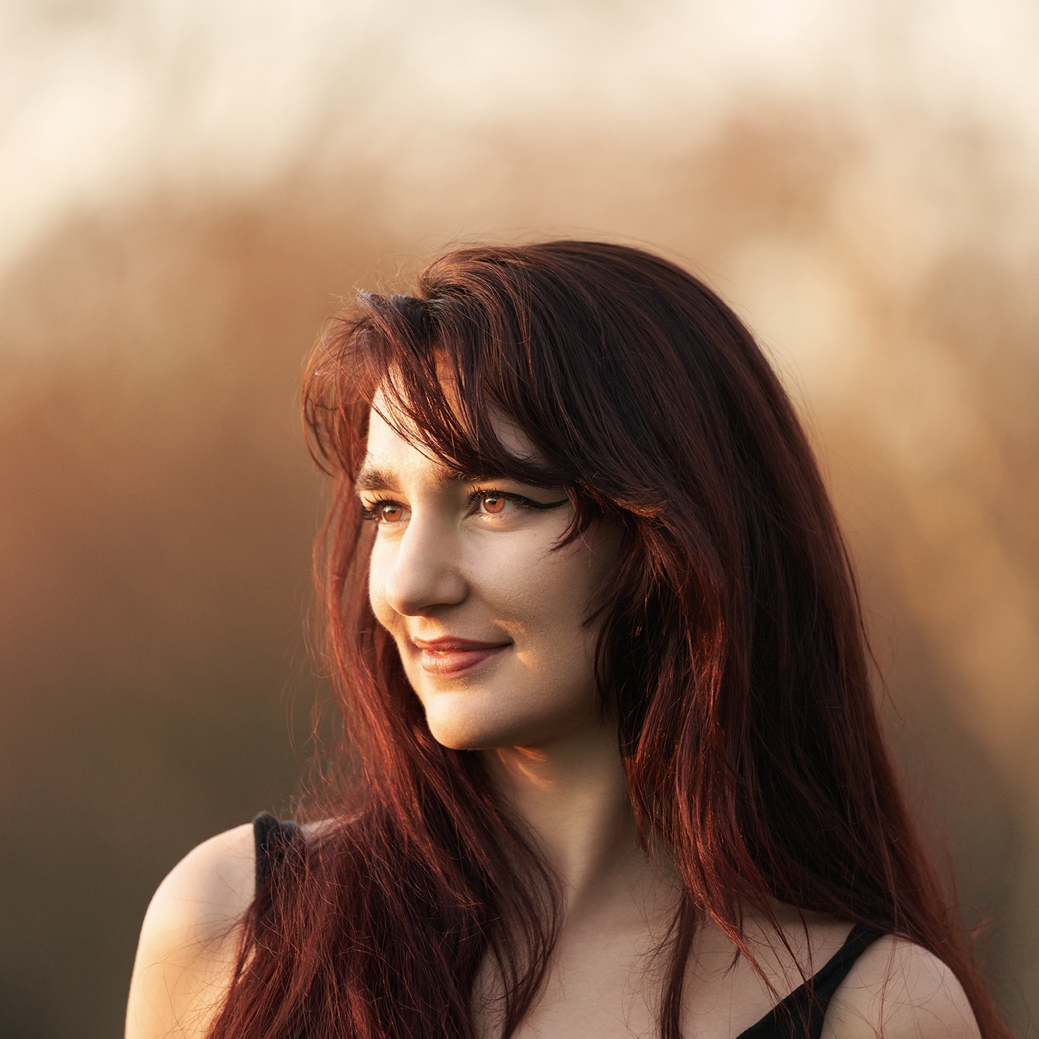 Woman with long brown hair smiling and looking off camera