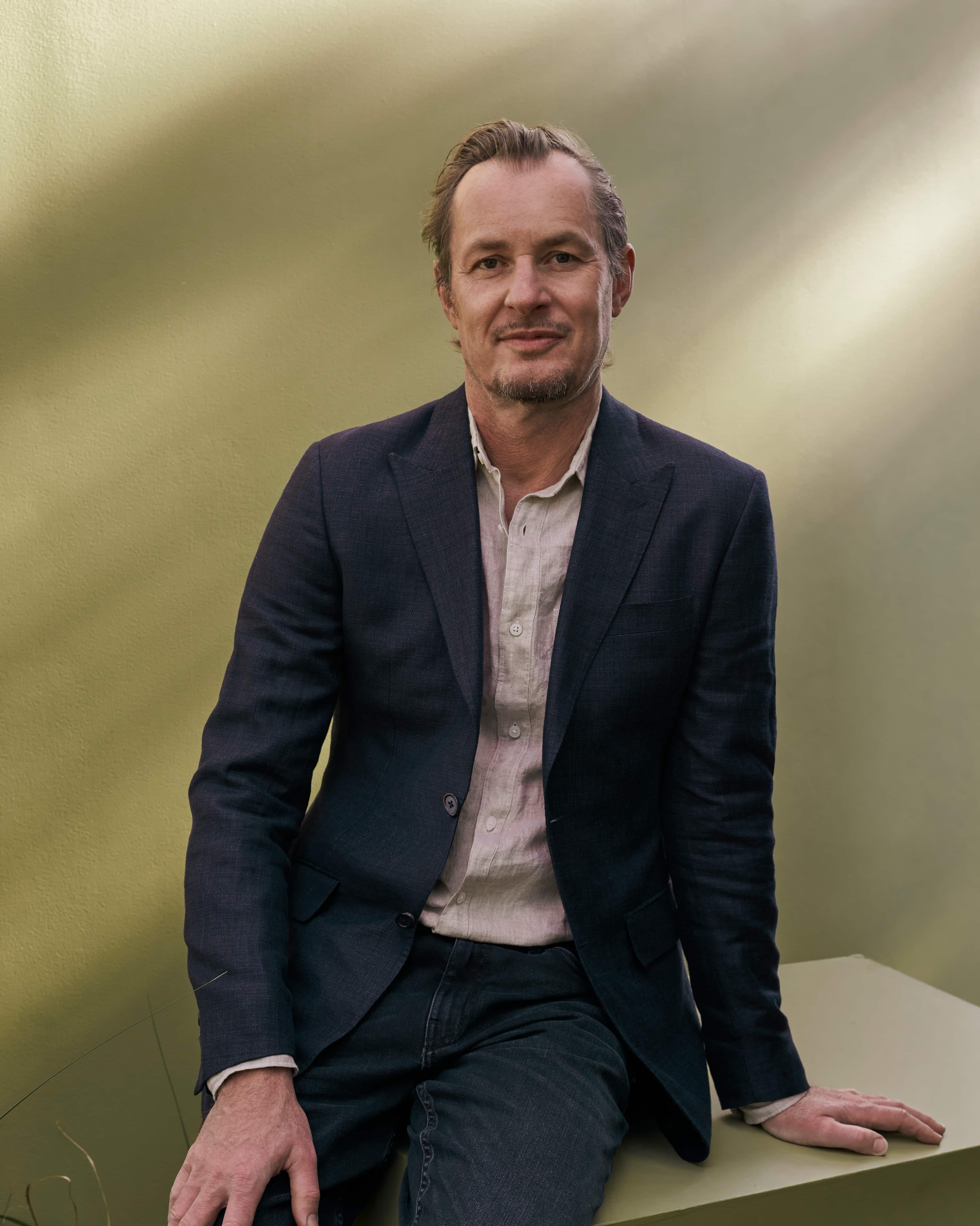 Man with blazer on looking directly at camera 