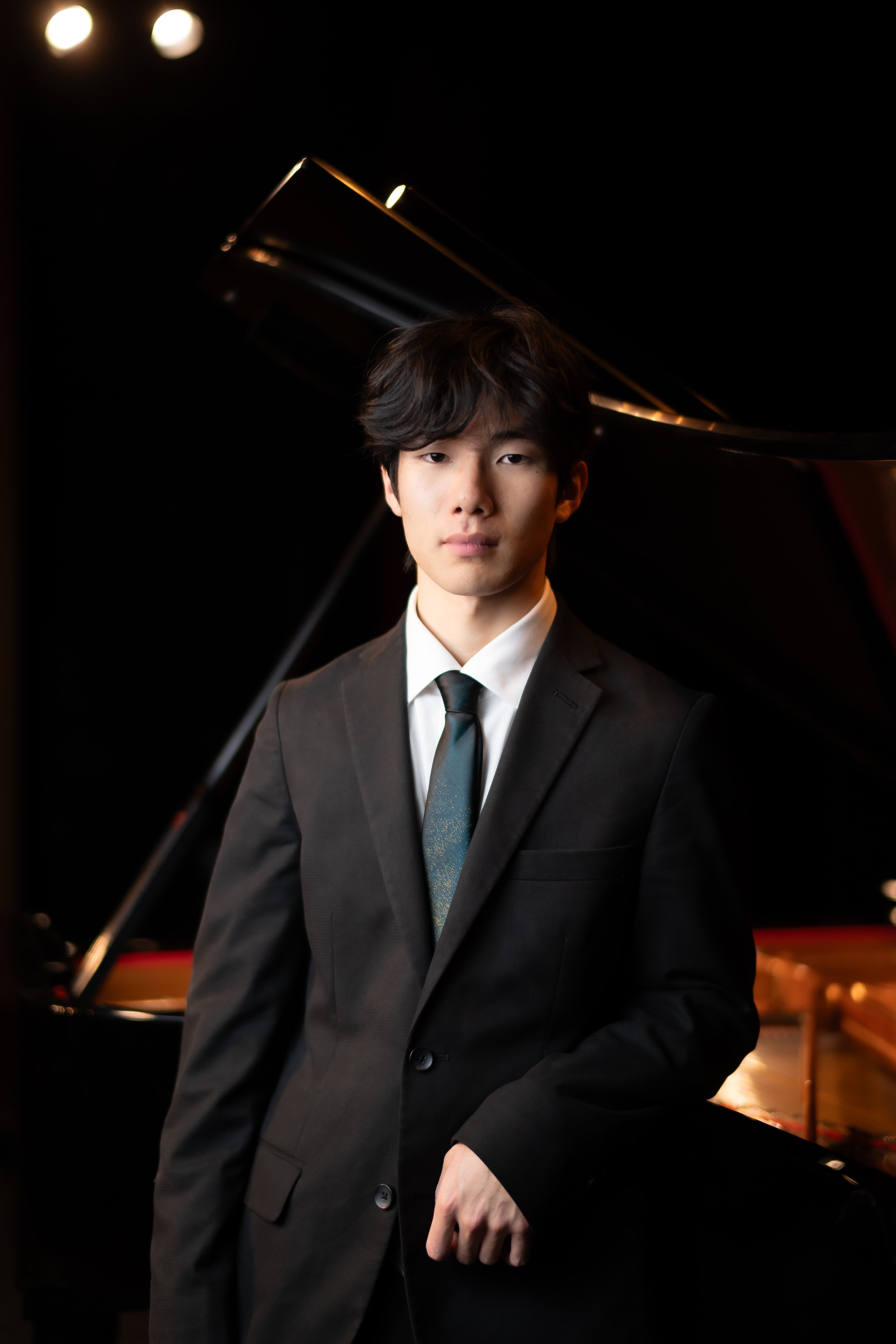 Man in black suit with blue tie and white collared shirt looking at camera