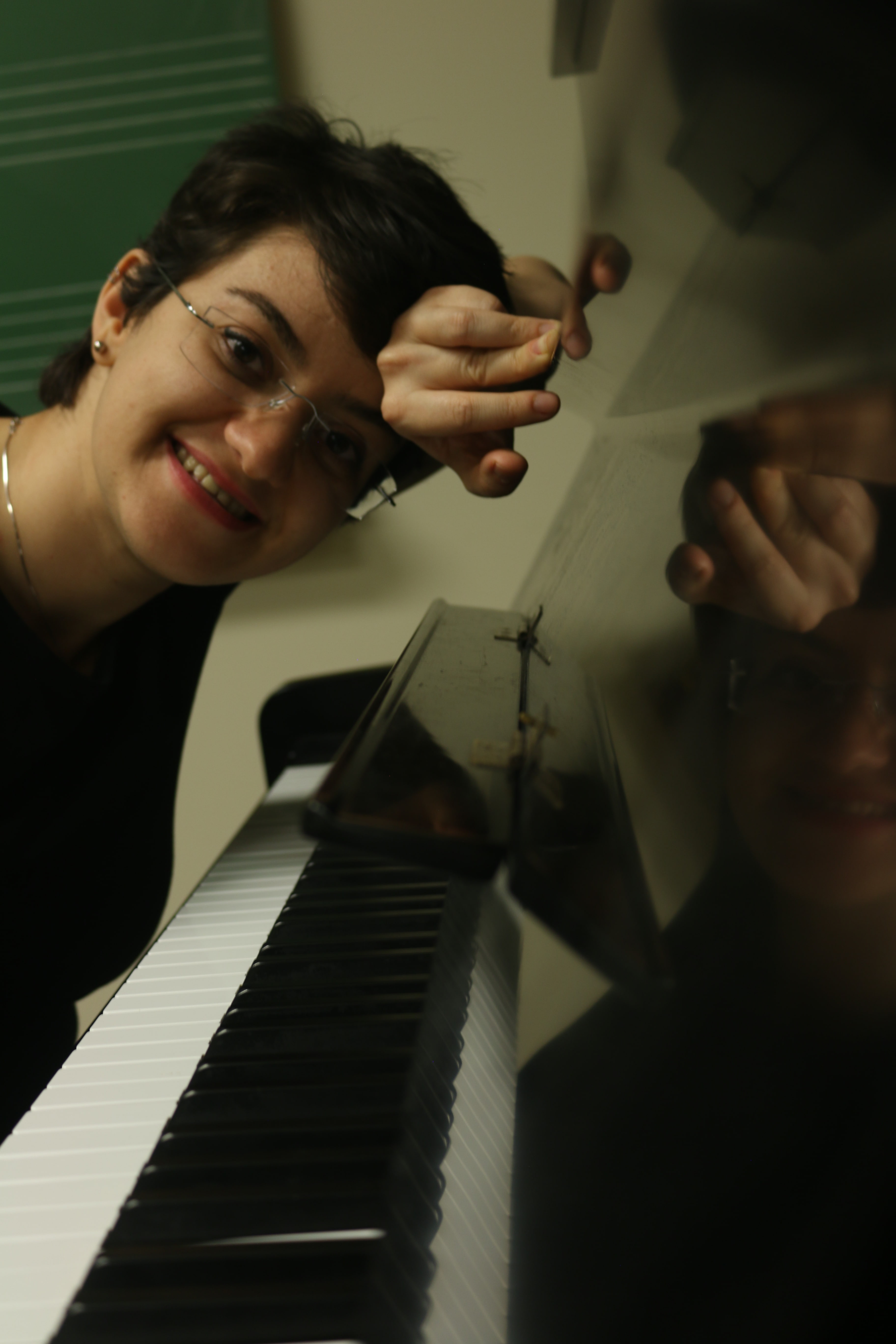 Person leaning on piano looking a the camera smilling