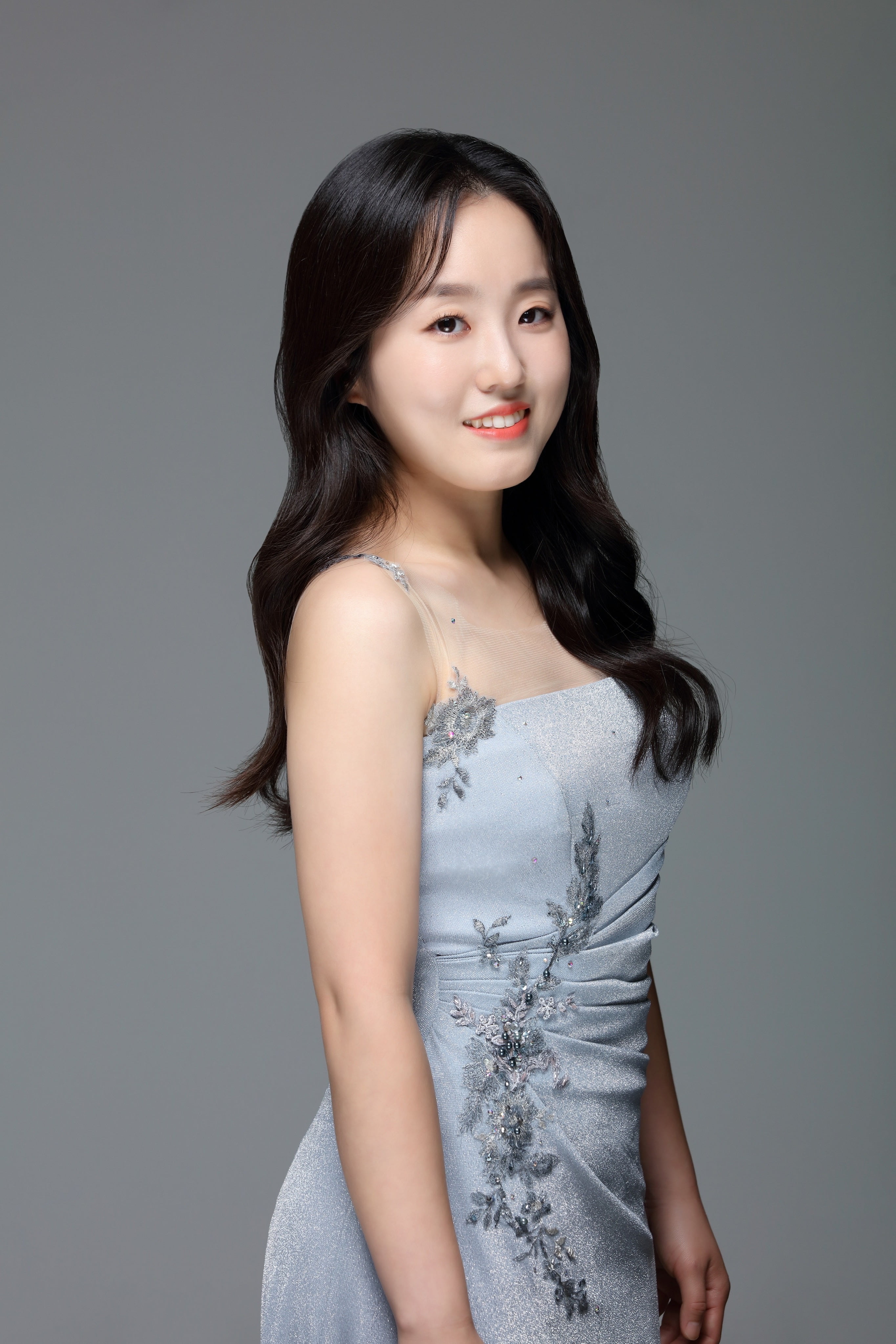 Woman with long dark hair wearing a formal dress smiling at the camera